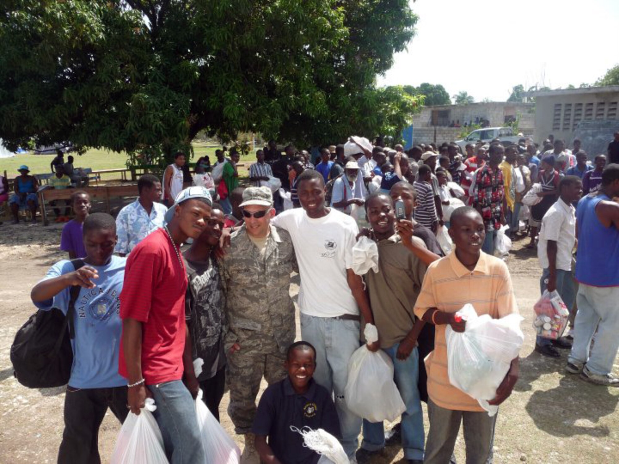 Master Sgt. Craig DeLorme, a pest management supervisor with the 128th Air Refueling Wing's Civil Engineering Squadron, Milwaukee, WI, stands with Haitians holding bags of food in Port-au-Prince, Haiti.  DeLorme deployed to Haiti on Feb. 23, 2010, to assist in the relief effort by reducing the pestilence in the affected area and helping to ensure clean water was available.  (photo submitted by Master Sgt. Craig DeLorme)