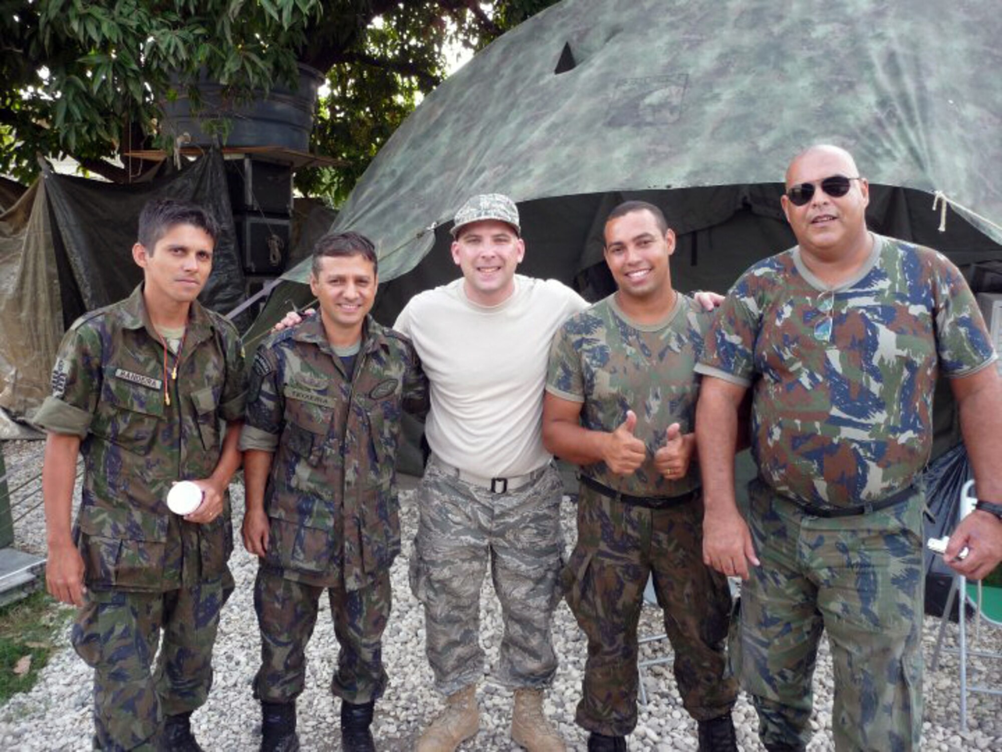 Master Sgt. Craig DeLorme, a pest management supervisor at the 128th Air Refueling Wing's Civil Engineer Squadron, Milwaukee, WI, shown center, gathers with Brazilian soldiers in a makeshift camp in Haiti.  DeLorme deployed to Port-au-Prince, Haiti, on Feb. 23, 2010, to assist in the international relief effort following a devastating earthquake on Jan. 12, 2010.  (photo submitted by Master Sgt. Craig DeLorme)
