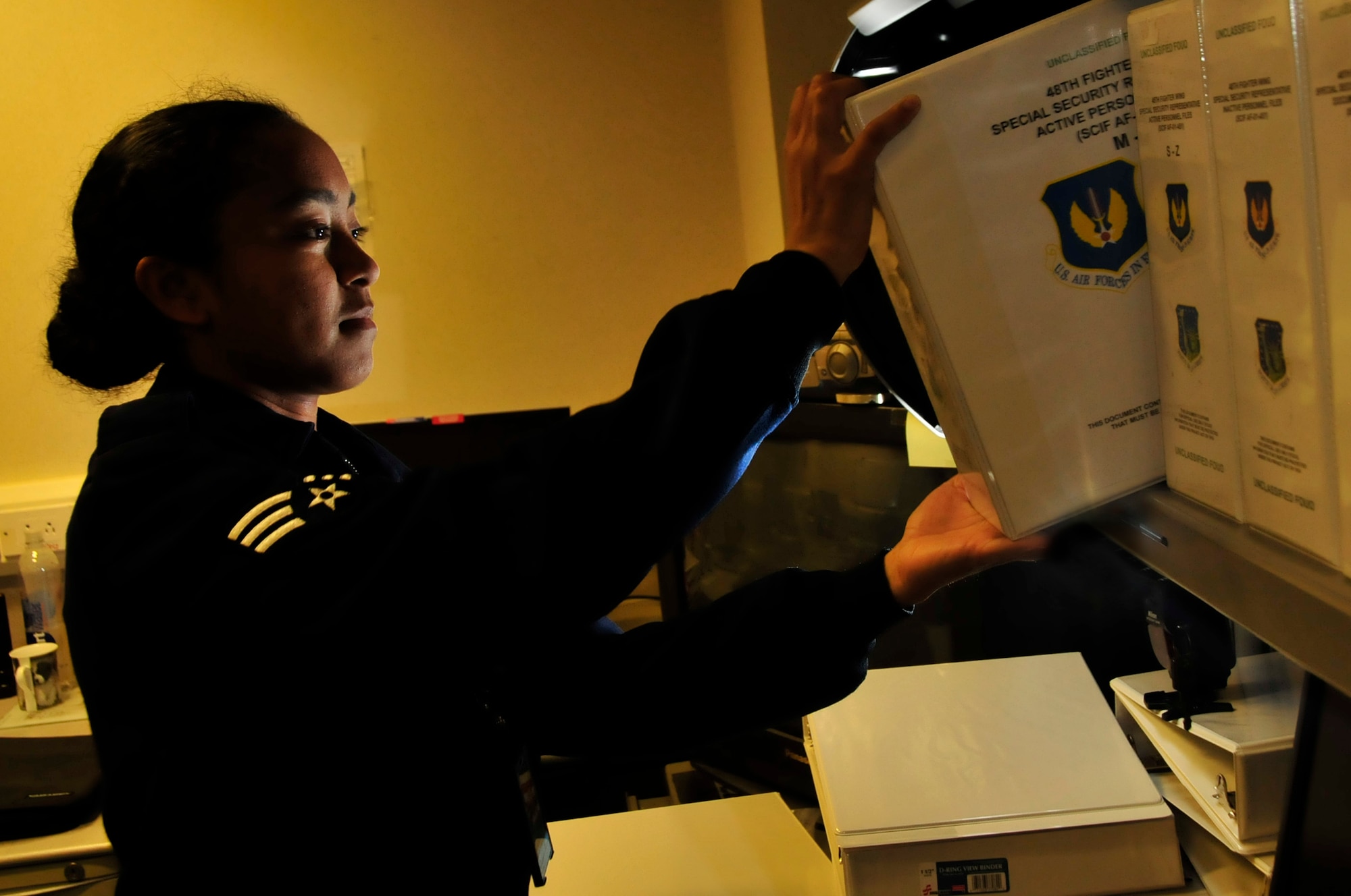 Senior Airman Jannie Cochran, 48th Fighter Wing Special Security representative, takes down a inactive personnel binder at RAF Lakenheath, England, June 21.   Airman Cochran was nominated for a Liberty Spotlight because she display the core value of 'Excellence in All We Do'. (U.S .Air Force photo/Airman 1st Class Eboni Knox)