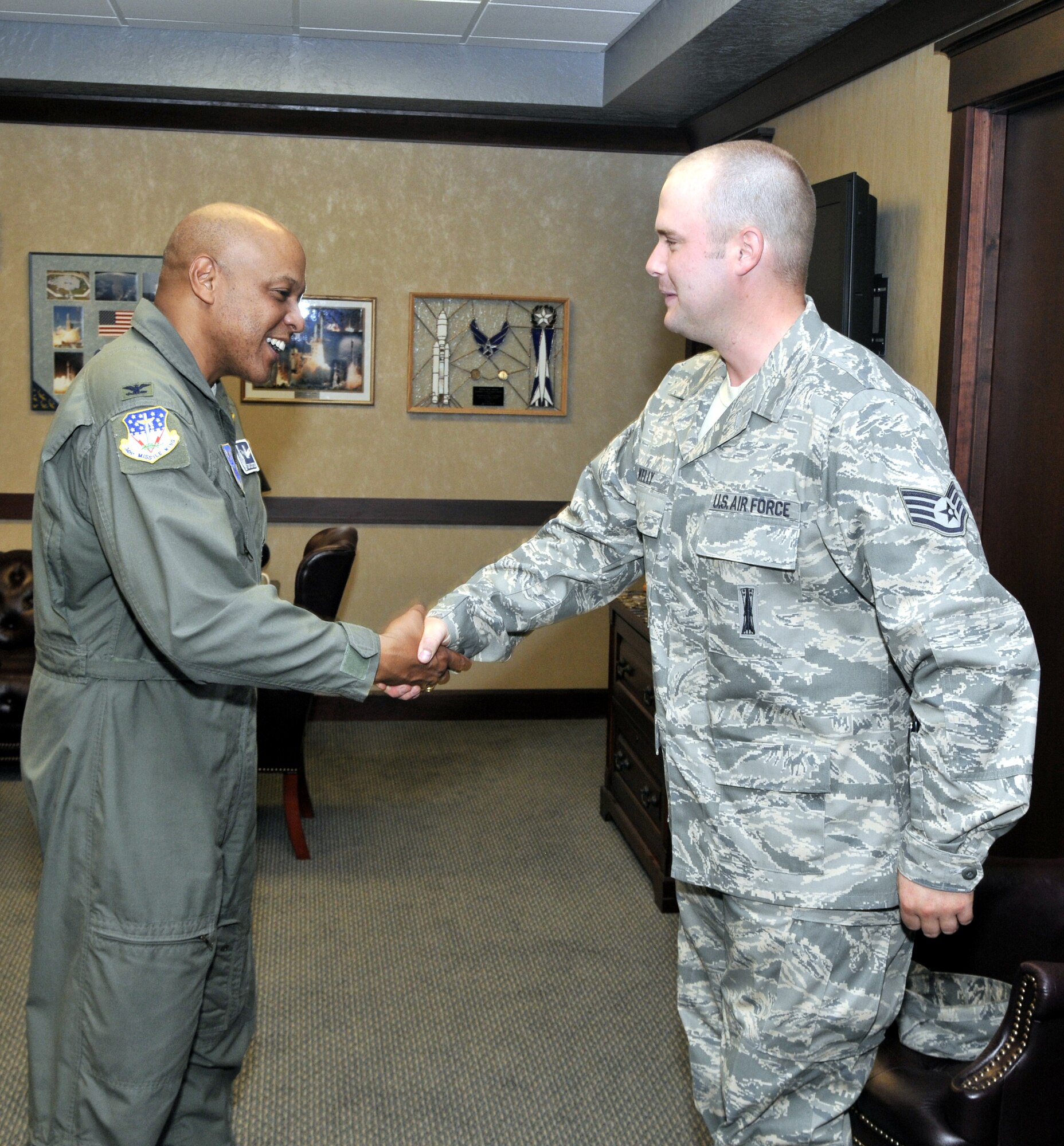 Col. Anthony Cotton, 341st Missile Wing commander, coins Staff Sgt. Joshua Kelly for completing his 100th safe driving mission in a payload transporter within the 13,800 square mile missile complex. Sergeant Kelly is a member of the 341st Missile Maintenance Squadron. (U.S. Air Force photo/John Turner)