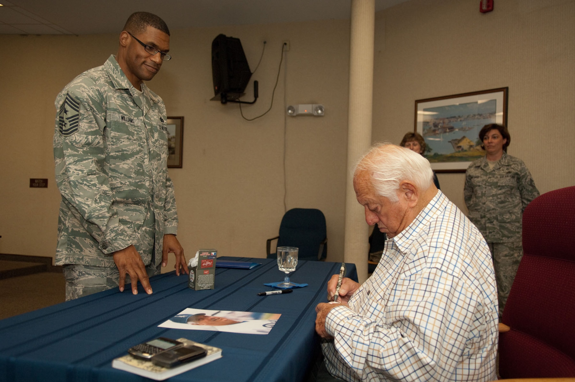 Chief Master Sgt. Kenneth A. Williams, Electronic Systems Center command chief, watches former Dodgers manager Tommy Lasorda autograph a baseball after speaking at the Hanscom Conference Center on June 18. The 82-year-old Lasorda shared plenty of jokes and stories with a large group of Airmen and civilians. (U.S. Air Force photo by Rick Berry)