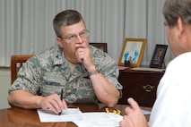 HANSCOM AIR FORCE BASE, Mass. – Col. Charles F. Thompson, 66th Air Base Wing commander, listens to Jim Taggart, Logistics Readiness Squadron director, explain information before signing documents during a recent meeting. Colonel Thompson hands off installation commander duties on June 30. (U.S. Air Force photo by Mark Wyatt)