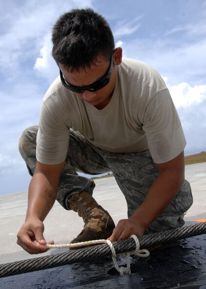 ANDERSEN AIR FORCE BASE, Guam -- Senior Airman Joel Grier, 36th Civil Engineer Squadron power production, ties a cable called a pendant to the flightline, June 19.Power production successfully completed the certification of two barrier arresting kits on the flightline, June 19. (U.S. Air Force photo by Airman 1st Class Anthony Jennings)