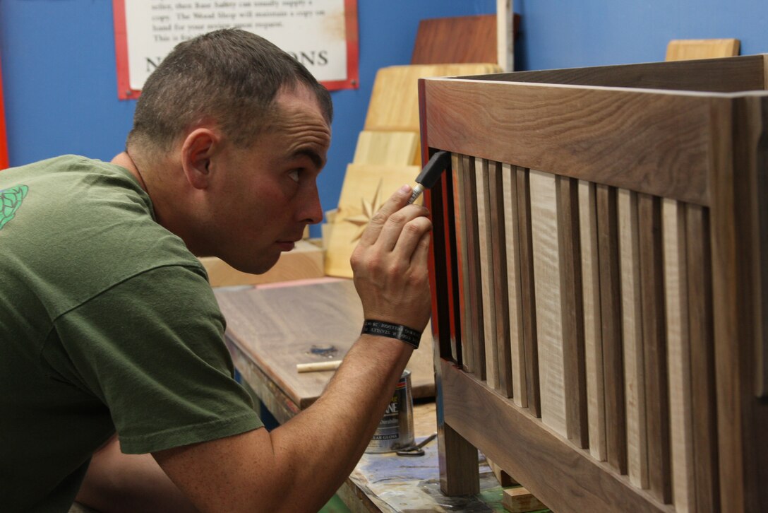 Staff Sgt. Stephen Foster, a Marine from the 3rd Battalion 4th Marine Regiment, paints the finish on a blanket chest he built at the Wood Hobby Shop, June 25.  Foster is also in the process of building a piano bench.
