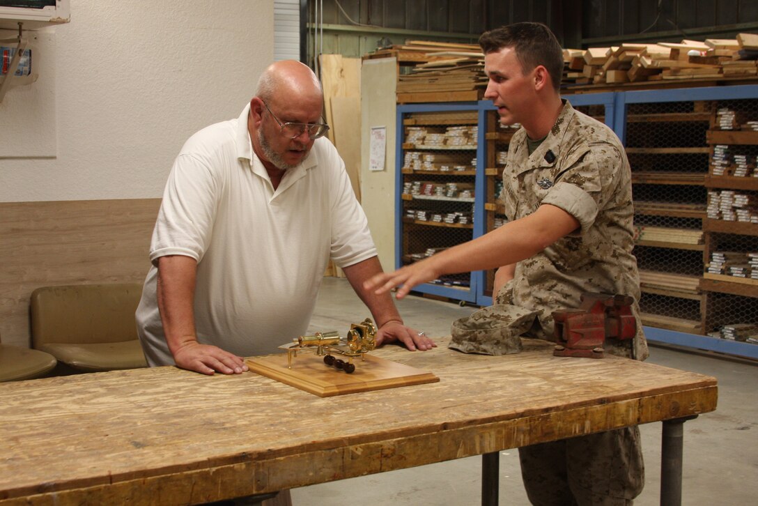 Ron Miller, the Manager of the Wood Hobby Shop helps a sailor plan out a plaque June 25. The plaque contains a mounted sextant.