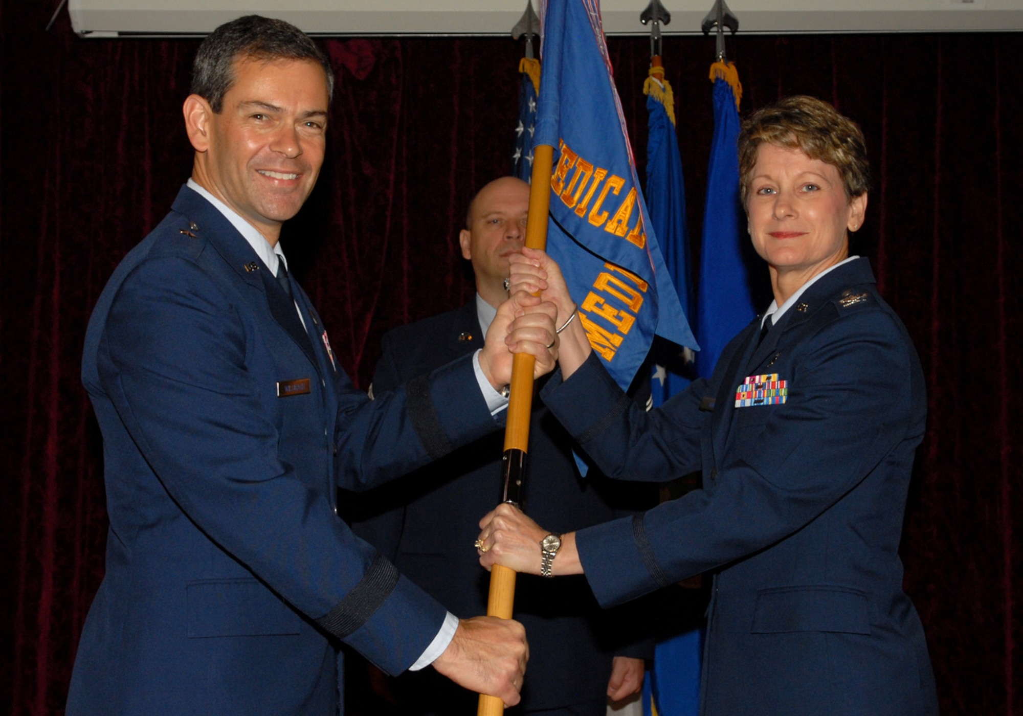 (Right) Col. Barbara King accepts the 18th Medical Group guidon from Brig. Gen. Ken Wilsbach, 18th Wing commander, during a change of command ceremony at the Rocker NCO Club June 25. As the new group commander, Colonel King manages nearly 500 health care professionals who are tasked with providing care for more than 55,000 beneficiaries at the largest outpatient clinic in Pacific Air Forces. She is also charged with managing the second largest neonatal intensive care unit in the Air Force, a dental laboratory and the only aeromedical staging flight in the Western Pacific. (U.S. Air Force/Junko Kinjo)