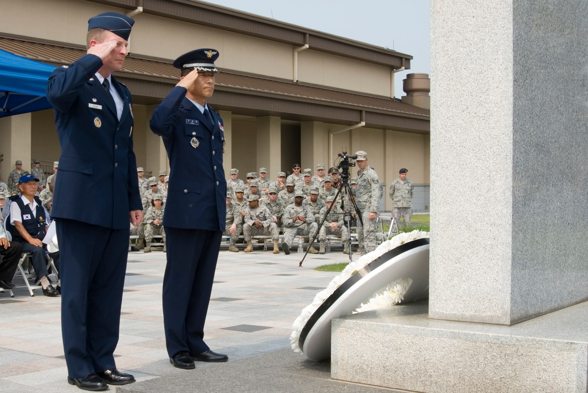 KUNSAN AIR BASE, Republic of Korea -- Col. John Dolan, 8th Fighter Wing commander, and Col. Jae Hun Choi, 38th Fighter Group commander, render a salute after laying a wreath in honor of the Korean War during the 60th anniversary of the Korean War commemoration ceremony held at the base flag pole.  In total, 51 Korean War veterans attended the ceremony which also included a three volley salute by seven 8th Security Forces Squadron members. (U.S. Air Force photo/Staff Sgt. Jonathan Pomeroy)