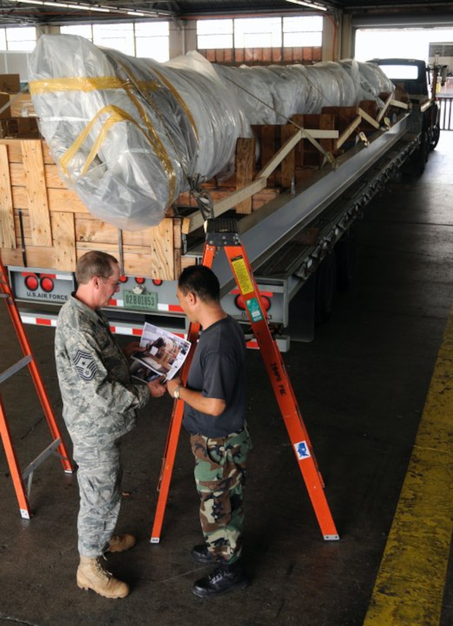 Command Chief Master Sgt. John Waller, from the 137th Air Refueling Wing Oklahoma Air National Guard, and Master Sgt. Daryl Oshiro, from 154th Wing Hawaii Air National Guard, make transportation plans for the 40-foot mast that was originally attached to USS Oklahoma (BB 37). The battleship Oklahoma, named after the 46th state, was sunk during the Dec. 7, 1941 attack. The mast itself was dredged up more than 60 years later to be transported to the Muskogee War Memorial in Oklahoma. (U.S. Navy photo by Mass Communication Specialist 2nd Class (SW) Mark Logico)