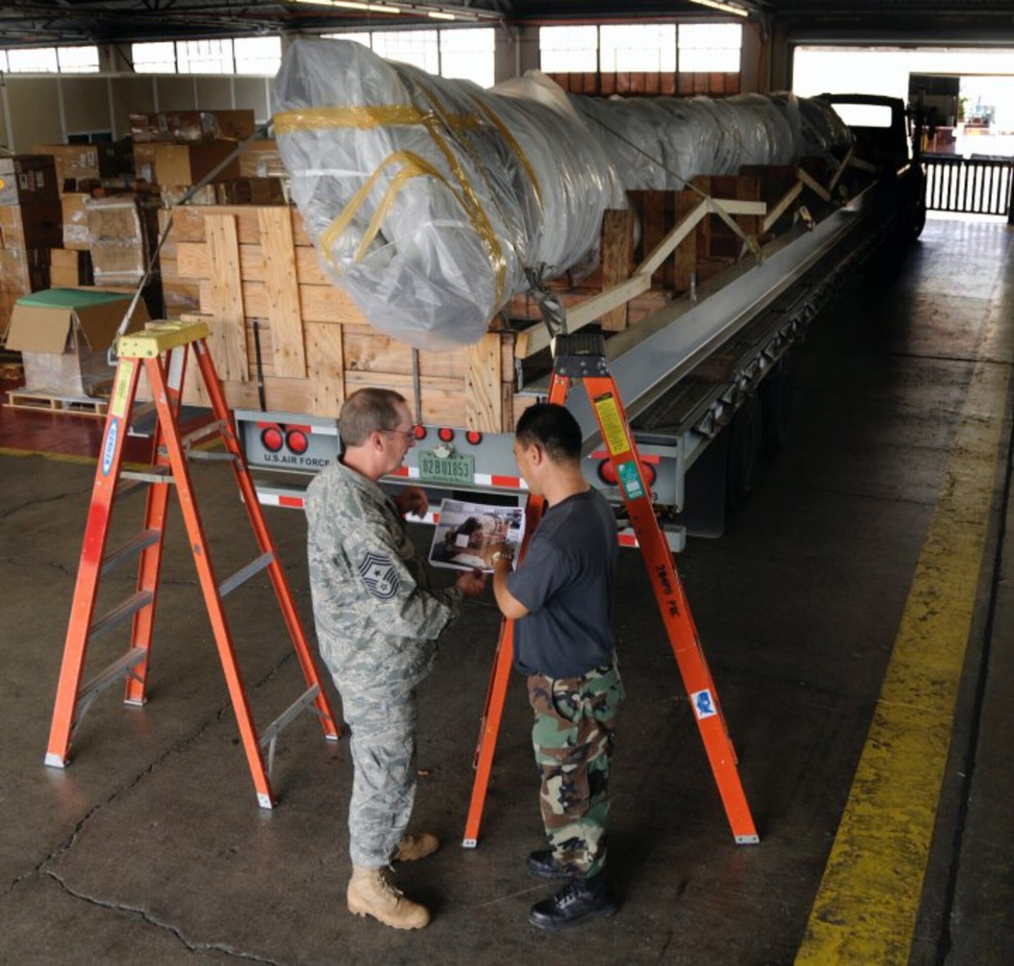 Command Chief Master Sgt. John Waller, from the 137th Air Refueling Wing Oklahoma Air National Guard, and Master Sgt. Daryl Oshiro, from 154th Wing Hawaii Air National Guard, make transportation plans for the 40-foot mast that was originally attached to USS Oklahoma (BB 37). The battleship Oklahoma, named after the 46th state, was sunk during the Dec. 7, 1941 attack. The mast itself was dredged up more than 60 years later to be transported to the Muskogee War Memorial in Oklahoma. (U.S. Navy photo by Mass Communication Specialist 2nd Class (SW) Mark Logico)