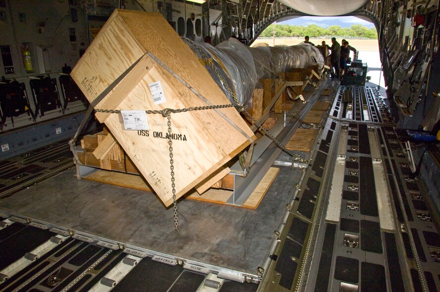 The 40-foot mast that was originally attached to USS Oklahoma is loaded on a C-17 on its way from Joint Base Pearl Harbor-Hickam to Muskogee War Memorial in Oklahoma. The battleship Oklahoma, named after the 46th state, was sunk during the Dec. 7, 1941 attack. The effort is part of a tribute to be made at the Muskogee War Memorial honoring the USS Oklahoma and her crew. (U.S. Air Force photo by Staff Sgt. Nathan Allen)