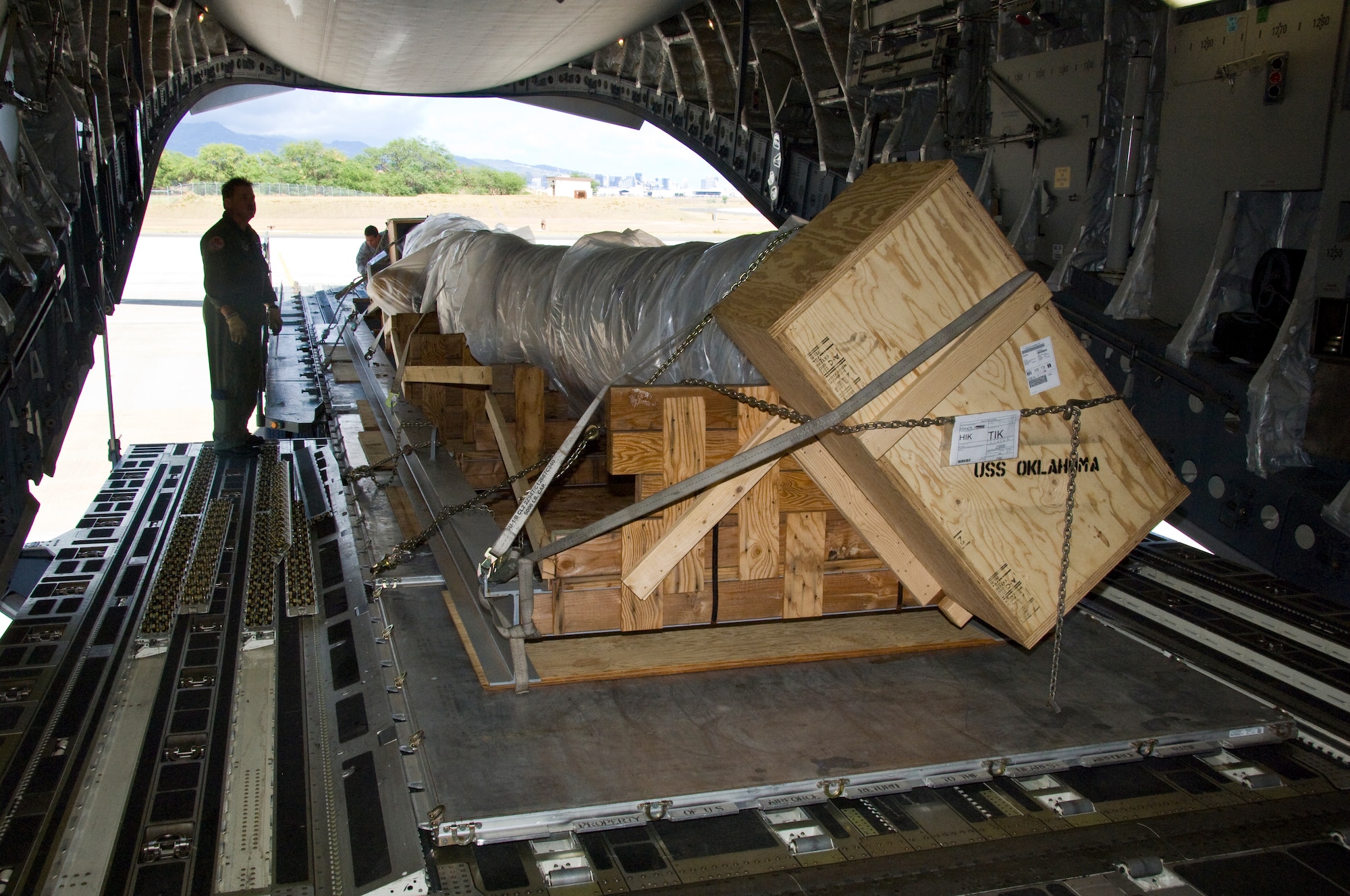 The 40-foot mast that was originally attached to USS Oklahoma is loaded on a C-17 on its way from Joint Base Pearl Harbor-Hickam to Muskogee War Memorial in Oklahoma. The battleship Oklahoma, named after the 46th state, was sunk during the Dec. 7, 1941 attack. The effort is part of a tribute to be made at the Muskogee War Memorial honoring the USS Oklahoma and her crew. (U.S. Air Force photo by Staff Sgt. Nathan Allen)