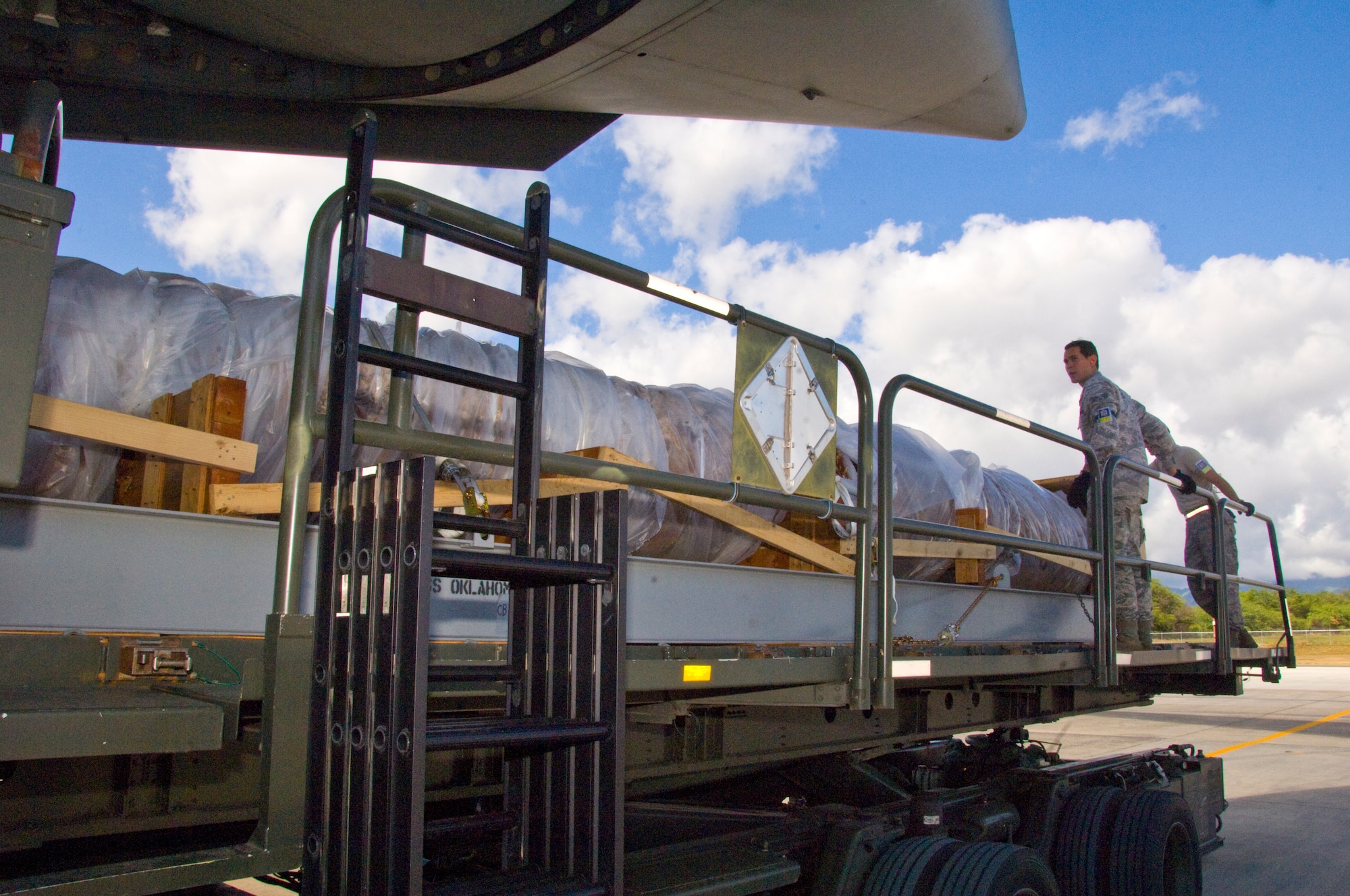 The 40-foot mast that was originally attached to USS Oklahoma is loaded on a C-17 on its way from Joint Base Pearl Harbor-Hickam to Muskogee War Memorial in Oklahoma. The battleship Oklahoma, named after the 46th state, was sunk during the Dec. 7, 1941 attack. The effort is part of a tribute to be made at the Muskogee War Memorial honoring the USS Oklahoma and her crew. (U.S. Air Force photo by Staff Sgt. Nathan Allen)
