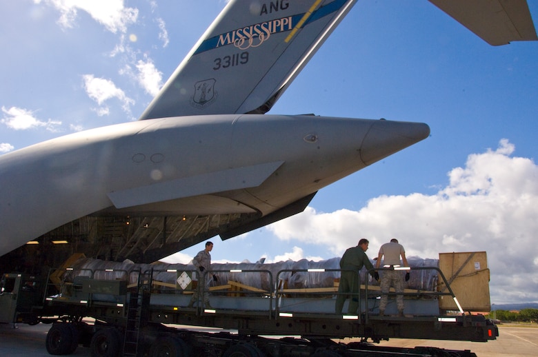 The 40-foot mast that was originally attached to USS Oklahoma is loaded on a C-17 on its way from Joint Base Pearl Harbor-Hickam to Muskogee War Memorial in Oklahoma. The battleship Oklahoma, named after the 46th state, was sunk during the Dec. 7, 1941 attack. The effort is part of a tribute to be made at the Muskogee War Memorial honoring the USS Oklahoma and her crew. (U.S. Air Force photo by Staff Sgt. Nathan Allen)