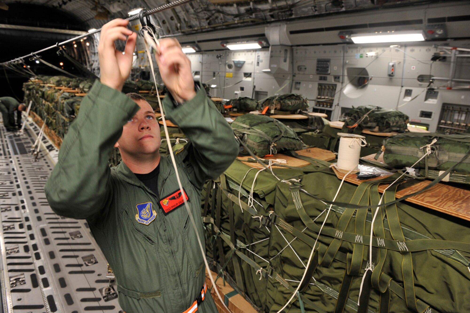 Joint Base Pearl Harbor-Hickam, Hawaii - 535th Airlift Squadron loadmaster Staff Sergeant Philip Vallenta reinforces an container delivery system bundle in preparation of a 25 bundle air drop totaling more than 90,000 pounds while at Joint Base Pearl Harbor-Hickam, Hawaii on June 24, 2010 in support of the Rim of the Pacific exercise (RIMPAC). This is the 22nd year of RIMPAC, a biennial exercise that promotes interoperability of more than 14 partner nations as a key element of regional stability.  There are 14 nations, 32 ships, five submarines, more than 170 aircraft and 20,000 personnel participating in RIMPAC from June 23 through Aug. 1, in the Hawaiian operating area in, and around, the islands of Hawaii. (U.S.  Air Force photo/Tech Sgt. Cohen A. Young) 