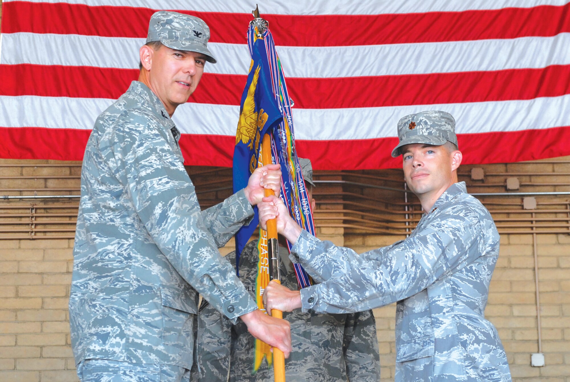 Col. Geoffrey Parkhurst, 56th Maintenance Group commander, passes the squadron guidon to Maj. James Blackman, incoming 56th Component Maintenance Squadron commander, June 21 during a change-of-command ceremony at Luke AFB, Ariz. (Photo by A1C Sandra Welch)