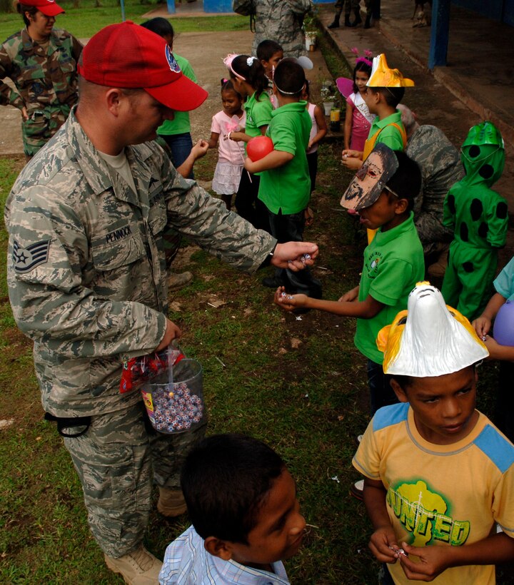 Staff Sgt. Christopher Pennock, 820th Expeditionary RED HORSE Squadron fire safety NCO, hands out chocolate to children from the Rio Iglesia elementary school June 24. Personnel from New Horizons Panama 2010 took time out of the construction schedule to support the school's conservation day festival. (U.S. Air Force photo/Tech. Sgt. Eric Petosky)