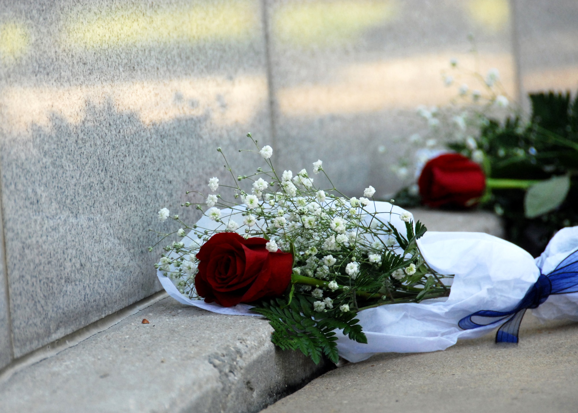 Single roses were laid at the foot the Khobar Towers Memorial Wall on the 14th anniversary of the tragedy during a ceremony June 25 at Eglin Air Force Base, Fla.  Almost 100 friends, family and current members of the 33rd Fighter Wing gathered for a remembrance ceremony near the memorial dedicated to the heroism of 12 Airmen lost. The 33rd FW suffered 105 wounded personnel and accounted for 12 of the 19 Airmen killed in the Khobar Towers terrorist attack June 25, 1996. (U.S. Air Force Photo/ Samuel King Jr.)