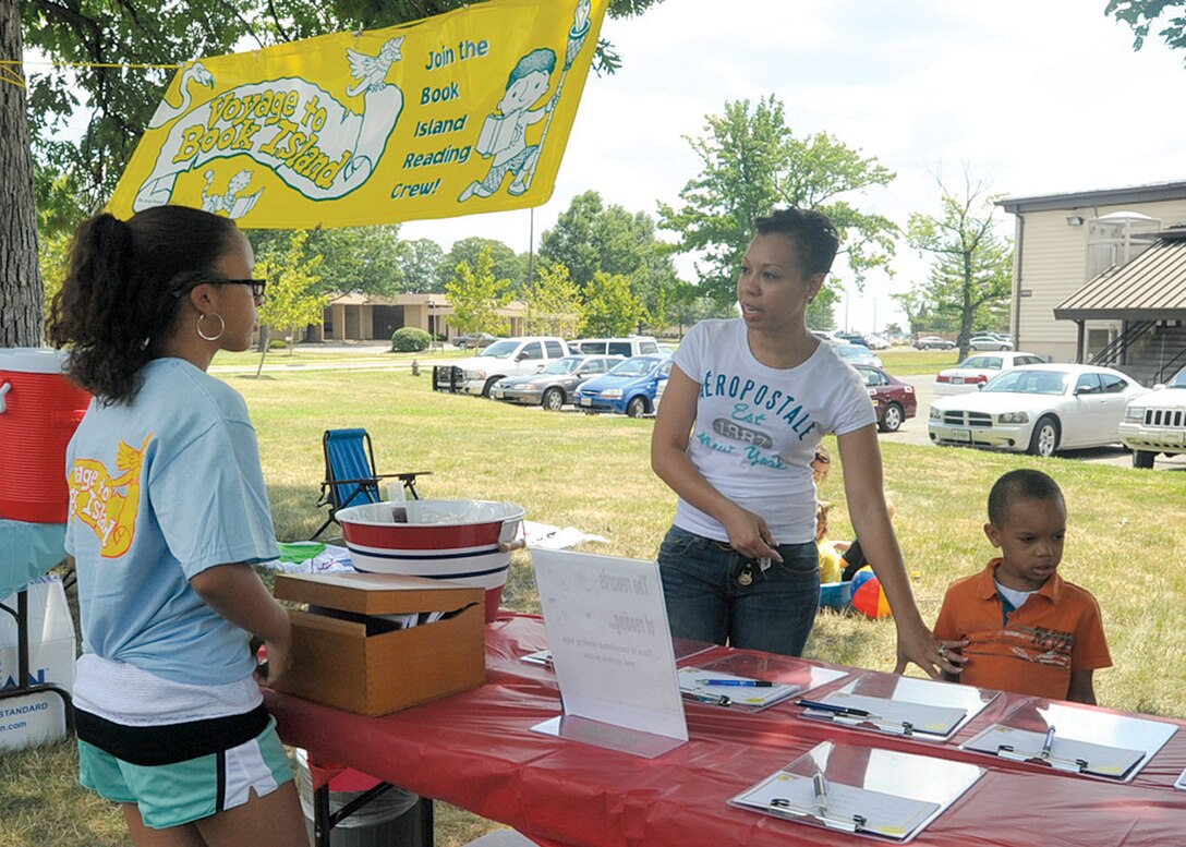 JOINT BASE ANDREWS, Md. --  Jenna Pearson, 14, Base Library aid, answers questions for a Joint Base Andrews member about registration for the Summer Reading Program. The program, which runs June 21 to August 21, encourages members to pick up reading program kits, and complete a reading log at the end of the week. The top readers in each age category, (1-5, 6-11 and 12-18) will receive prizes at the conclusion of the program. The kick-off reading program theme is ‘Voyage to Book Island.' The Summer Reading Program is scheduled to culminate with an awards ceremony on Aug. 21. Jenna is the daughter of Tech. Sgt. (ret.) Keith Pearson. (U.S. Air Force photo by Bobby Jones)