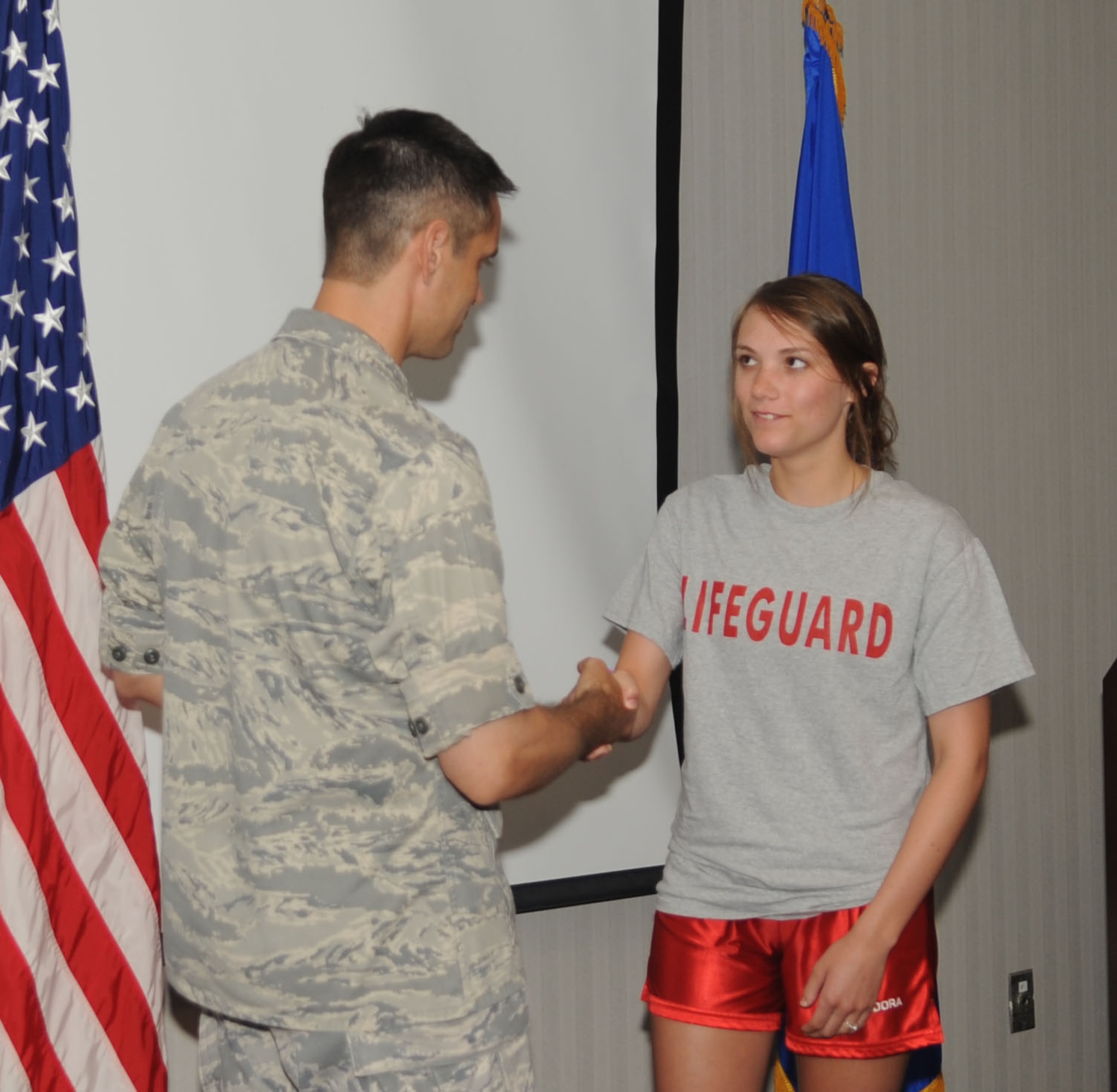 BARKSDALE AIR FORCE BASE, La. -- Colonel Steven Basham, 2d Bomb Wing commander, presents Barksdale lifeguard, Kasey Schluter, with his coin. Ms. Schluter was recognized for her heroic efforts that saved the life of a young boy who almost drowned at the North Pool May 28. (U.S. Air Force photo by Senior Airman Alexandra Boutte) (RELEASED)