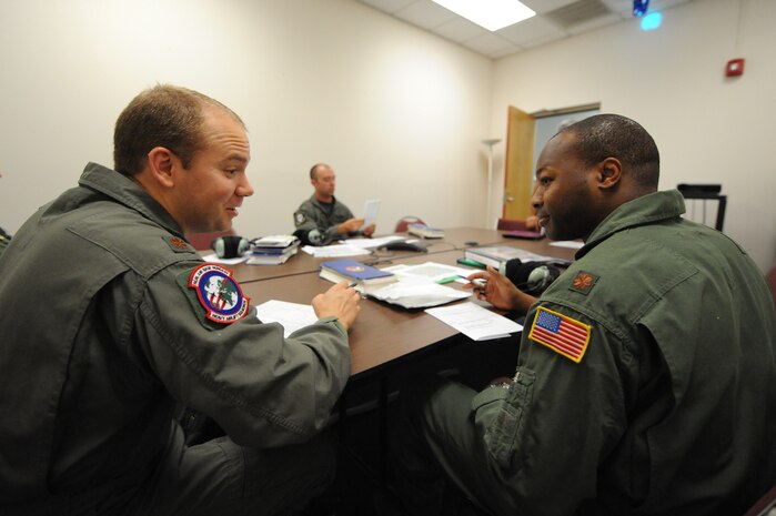 U.S. Air Force Maj. Brian Nicosia discusses details on flight plans with Maj. Patrick Brady-Lee prior to flying in the C-17 simulator on Joint Base Charleston, S.C., June 21, 2010. Major Nicosia is the chief of tactics with the Heavy Airlift Wing at Papa Air Base, Hungary, and is visiting JB CHS for quarterly pilot training. Major Brady-Lee is the assistant director of operations with the 16th Airlift Squadron. (U.S. Air Force photo/James M. Bowman)(Released)
