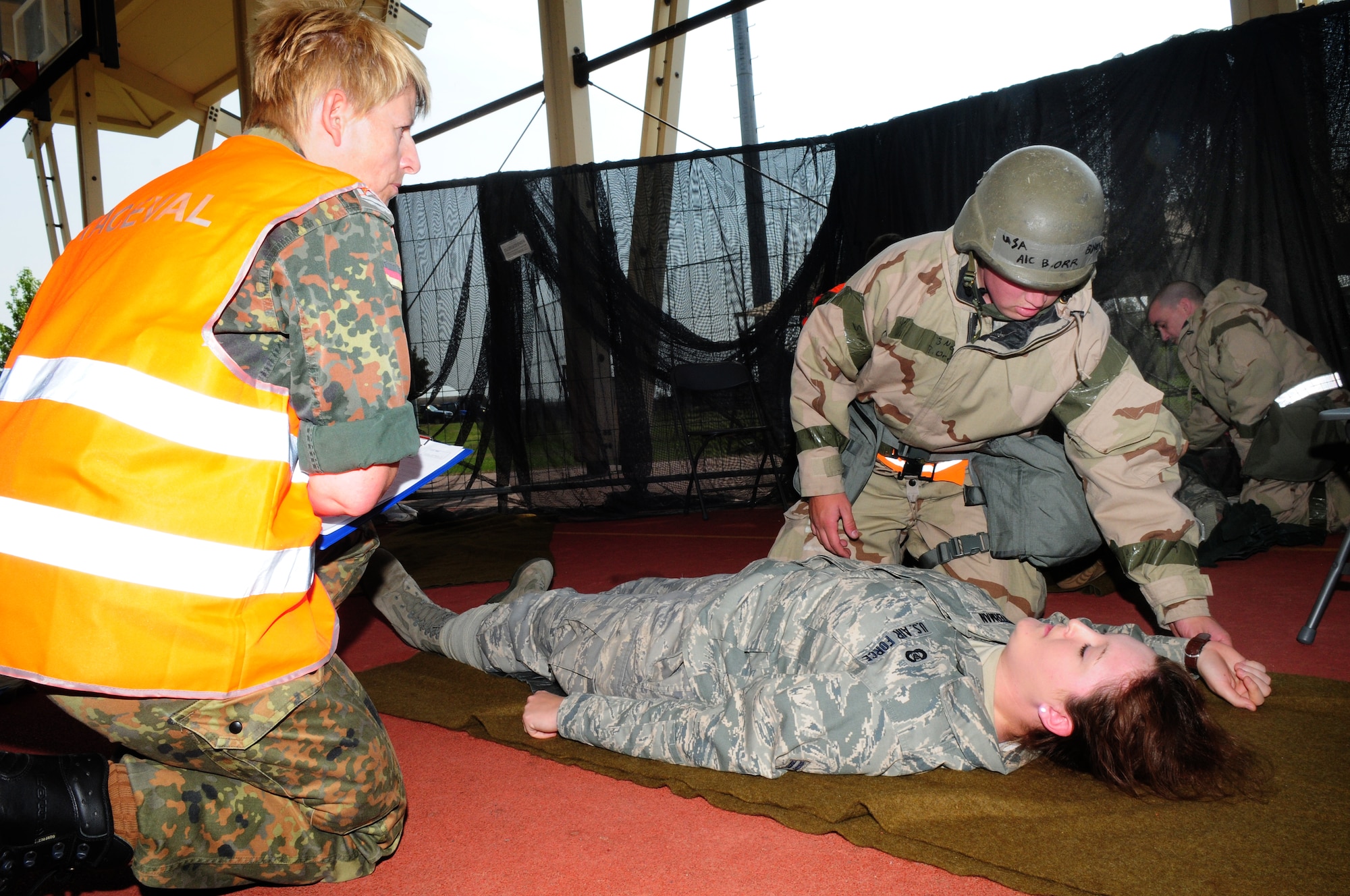 SPANGDAHLEM AIR BASE, Germany – An inspector evaluates Airman 1st Class Brandon Orr’s application of self-aid and buddy care principles to Airman Eden Winterman, a simulated gunshot wound victim during individual core competency skills assessments conducted here June 25.  The ICCS assessments are one portion of the NATO force evaluation Spangdahlem has participated in this week. These skills are critical assets military members need to proficiently conduct contingency operations that may require crisis intervention, such as deployments or NATO missions. (U.S. Air Force photo/Staff Sgt. Heather M. Norris)