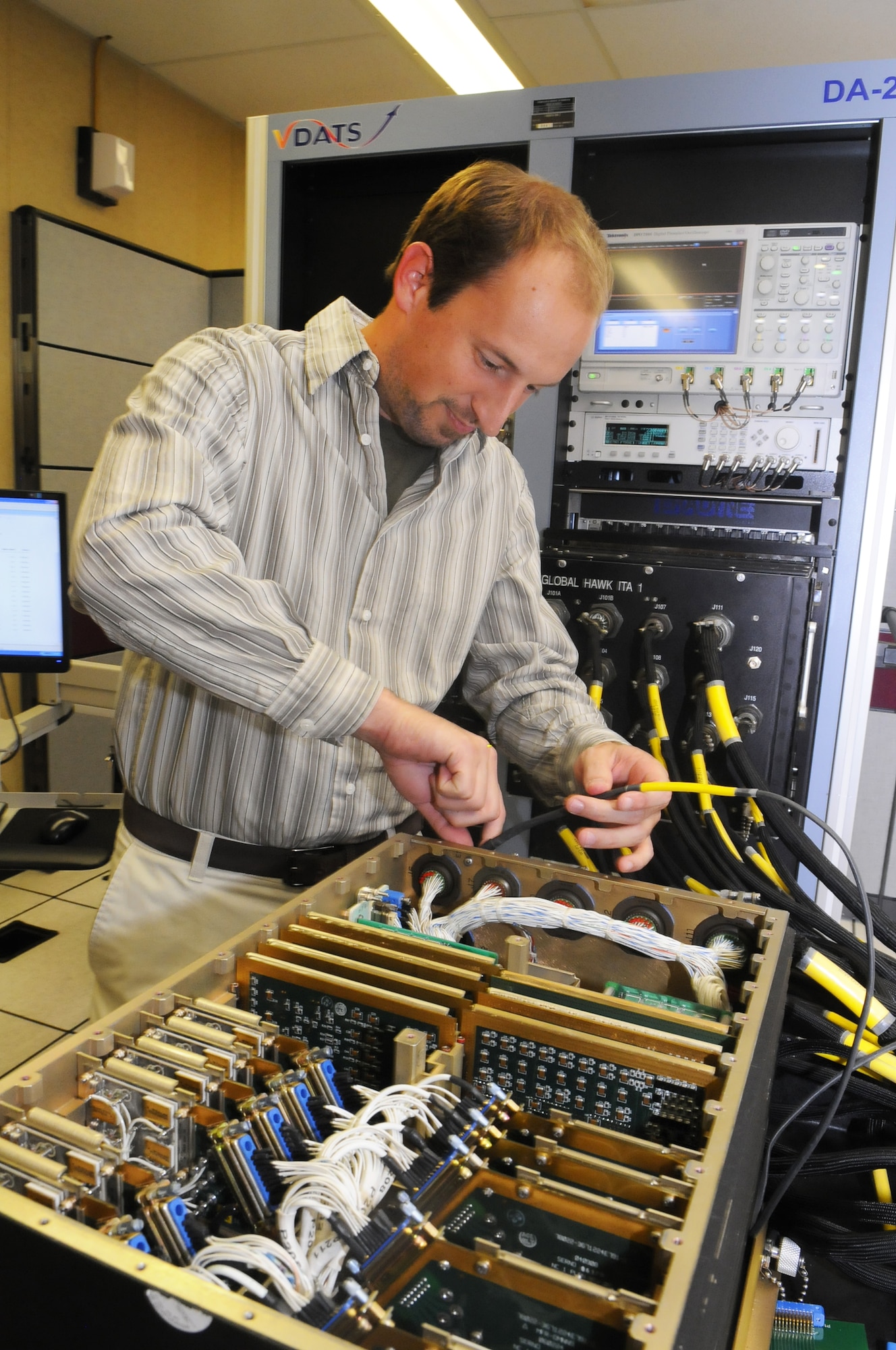 Matthew Chiasson connects the Global Hawk Line Replacible Unit to the VDATS automatic test equipment tester. U. S. Air Force photo by Sue Sapp