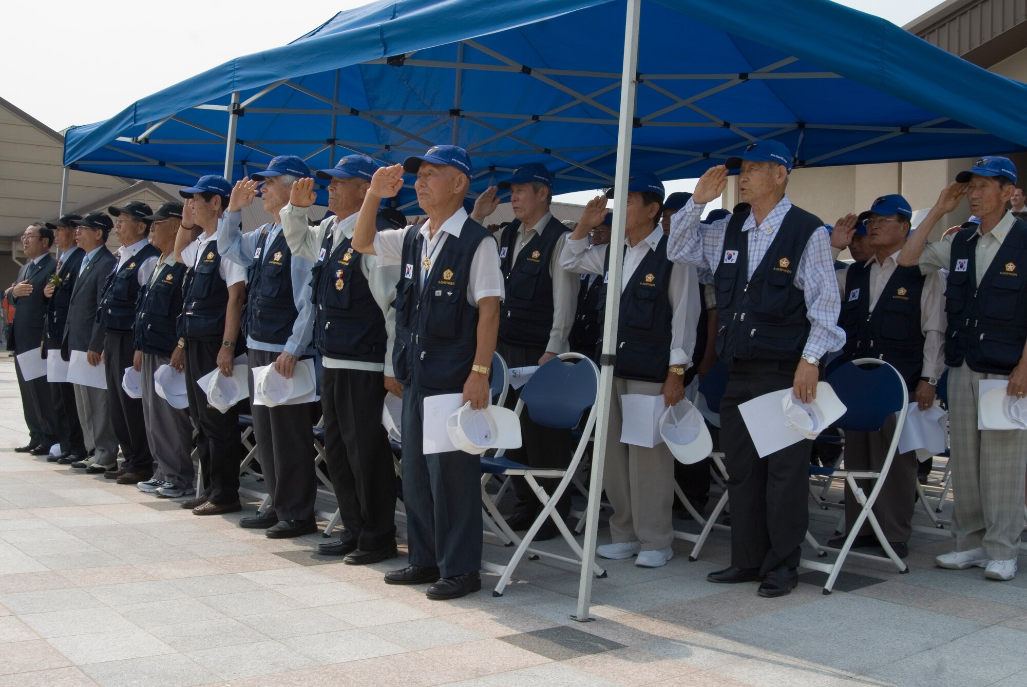 KUNSAN AIR BASE, Republic of Korea -- Korean War veterans render a salute during the American and South Korean national anthems during the 60th anniversary of the Korean War commemoration ceremony held at the base flag pole. In total, 51 Korean War veterans attended the ceremony which also included a three volley salute by seven 8th Security Forces Squadron members. (U.S. Air Force photo/Staff Sgt. Jonathan Pomeroy)