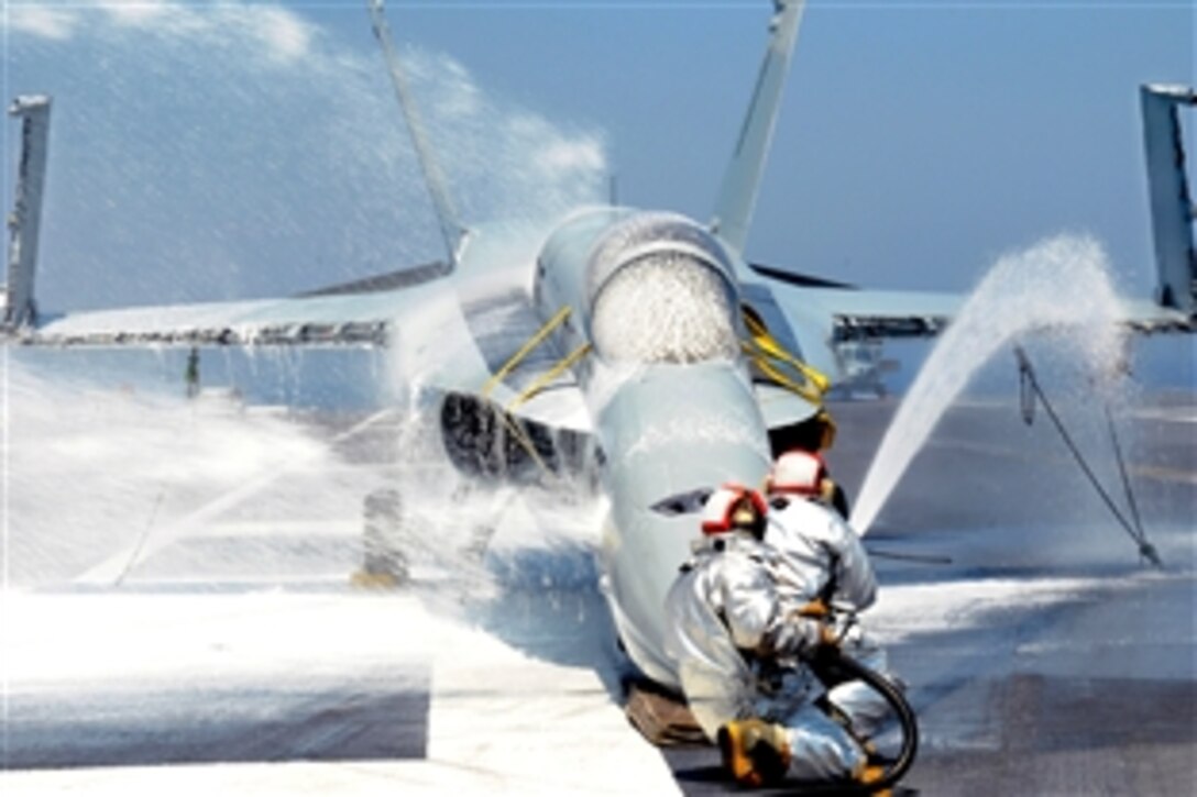 U.S. Navy sailors assigned to the aircraft carrier USS George H.W. Bush's crash and salvage division spray water on an F/A-18 Hornet training aircraft during a flight deck firefighting drill, under way in the Atlantic Ocean, June 21, 2010. 