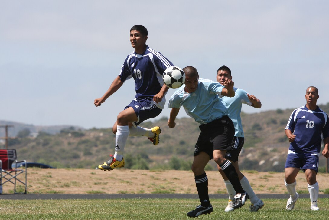 Oscar Serrano, a player for the Marine Corps Air Station Miramar, Calif., installation team, heads the ball as Carlos Iruegas, a player for the Combat Center's installation soccer team, flies through the air during a tournament game June 26 at Marine Corps Base Camp Pendleton, Calif. The game ended with Twentynine Palm's victory 5-1.