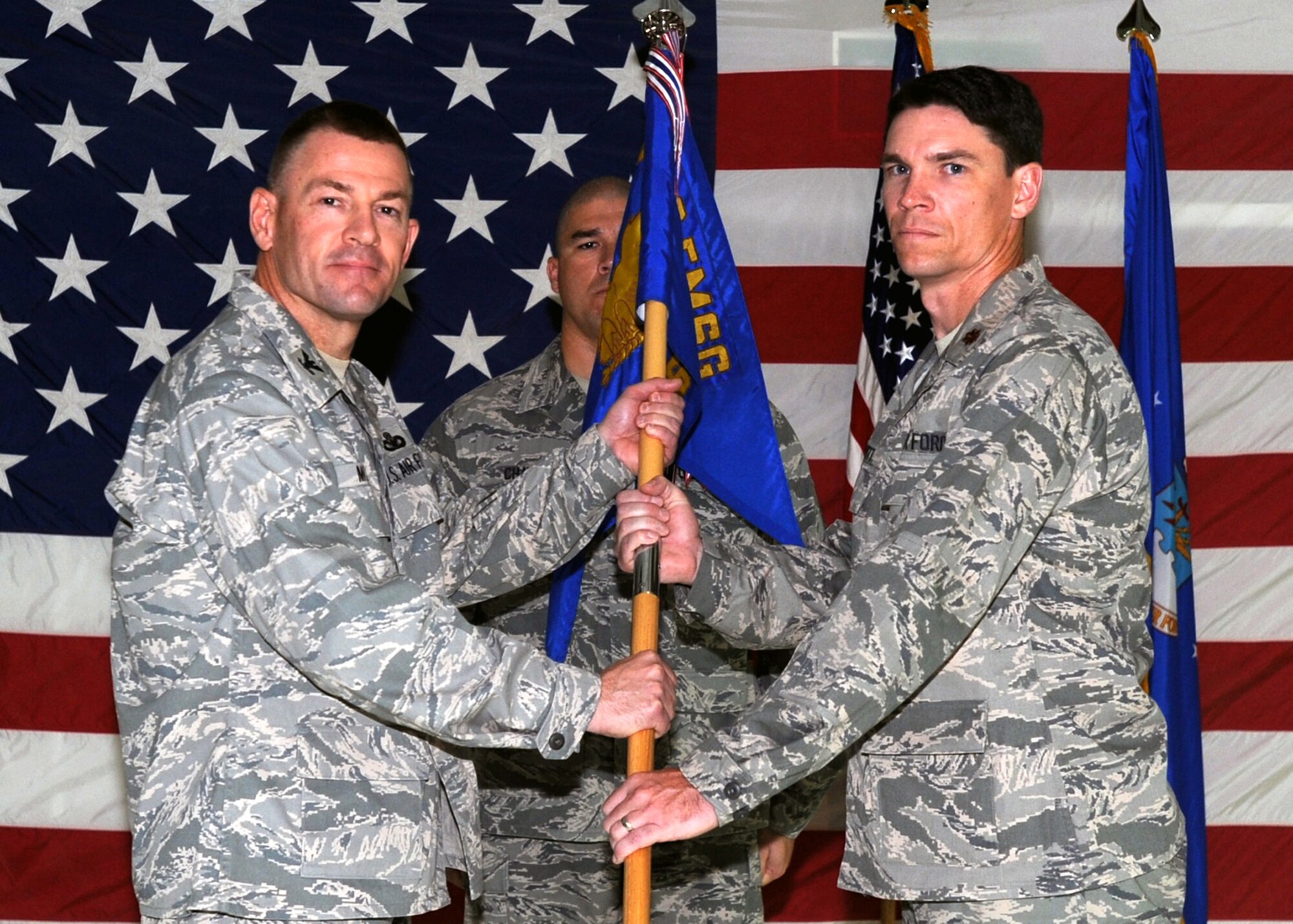 SOUTHWEST ASIA ? U.S. Air Force Col. Richard McComb (left), 386th Expeditionary Mission Support Group commander, passes the 386th Expeditionary Communications Squadron guidon to Maj. James Hewitt, the new 386th ECS commander, during a change-of-command ceremony here June 26, 2010, at the base passenger terminal. Major Hewitt assumed command after Maj. Roy Rockwell relinquished command. (U.S. Air Force photo by Senior Airman Laura Turner/Released)