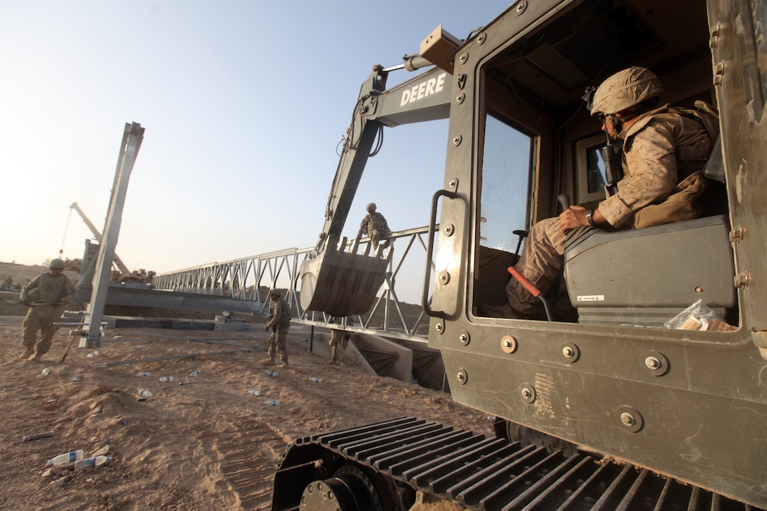 A Marine heavy equipment operator lends a hand to Army personnel by transporting large sections of a bridge during a bridge construction project in northern Marjah, Helmand Province, Afghanistan, June 26. For nearly a week, Marines, sailors and soldiers worked together to build a bridge in order to provide more freedom of movement for locals and safer access to Marjah for coalition forces.