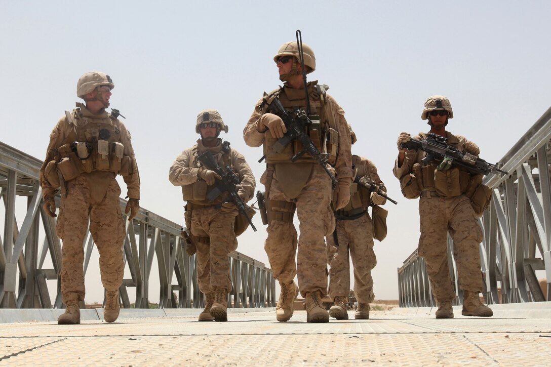 A security team led by Lt. j.g. Johnathan R. Flynn (middle), officer in charge of Naval Mobile Construction Battalion 5, escorts Lt. Col. Brian Christmas (far left), battalion commander of 3rd Battalion, 6th Marines, across a newly-constructed bridge in northern Marjah, Helmand Province, Afghanistan, June 26. Marines, sailors and soldiers worked side-by-side for about a week constructing the bridge, which will provide more freedom of movement for locals and safer access to Marjah for coalition forces.