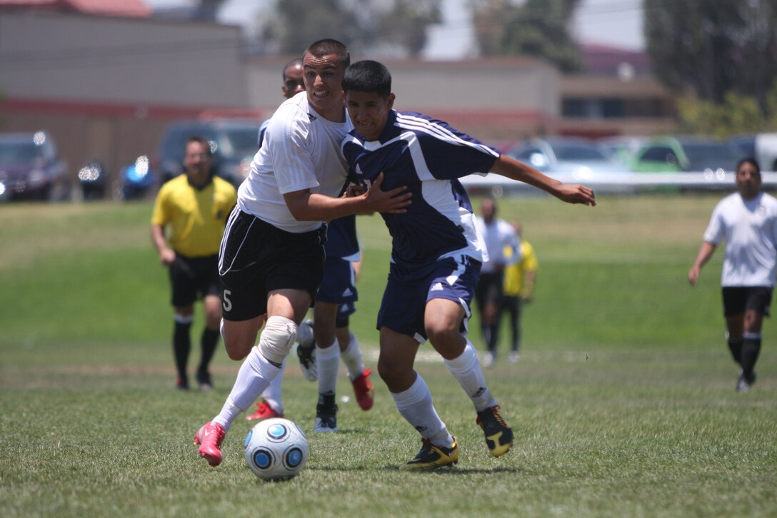Carlos Iruegas [right], a player for the Combat Center's installation soccer team, pushes against a player for the Marine Corps Base Camp Pendleton, Calif., team, as they fight for possession of the ball June 27 at Camp Pendleton.