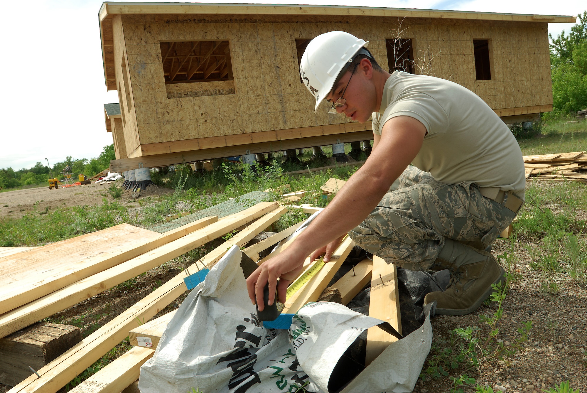 Members of the 433rd Civil Engineering Squadron conduct a humanitarian mission in the Red Lake Indian Reservation for the Red Lake band of Chippewa Indians, just outside of Bemidji, Minnesota. Senior Airman Jaime Payen, 433rd CES electrician, measures a length of framing lumber to use in an installation of an electrical panel. The board, a scrap piece from framing one of the houses in the background, happened to be exactly the right size. (U.S. Air Force photo/Airman 1st Class Brian McGloin)