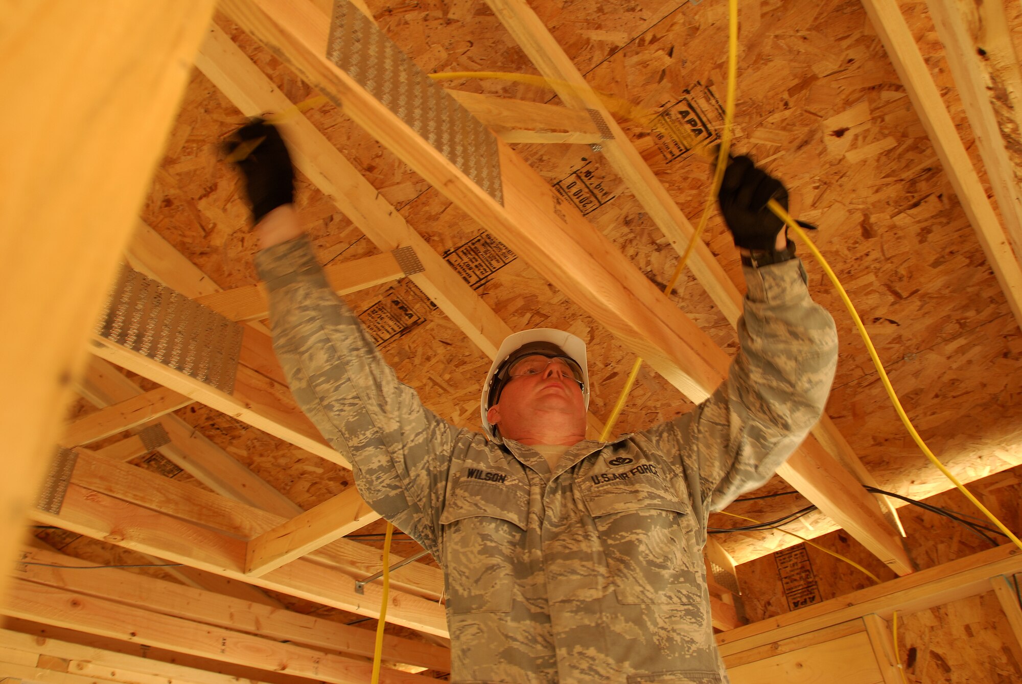 Members of the 433rd Civil Engineering Squadron conduct a humanitarian mission in the Red Lake Indian Reservation for the Red Lake band of Chippewa Indians, just outside of Bemidji, Minnesota. Master Sgt. Curtis Wilson runs wire over ceiling joists from an electrical panel to where a bathroom ceiling fan will be.(U.S. Air Force photo/Airman 1st Class Brian McGloin)