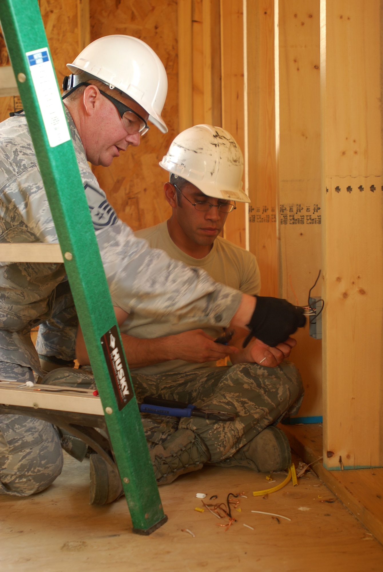 Members of the 433rd Civil Engineering Squadron conduct a humanitarian mission in the Red Lake Indian Reservation for the Red Lake band of Chippewa Indians, just outside of Bemidji, Minnesota. Master Sgt. Curtis Wilson, 433rd CES, gives some wiring advice to Staff Sgt. David Bustos. (U.S. Air Force photo/Airman 1st Class Brian McGloin)