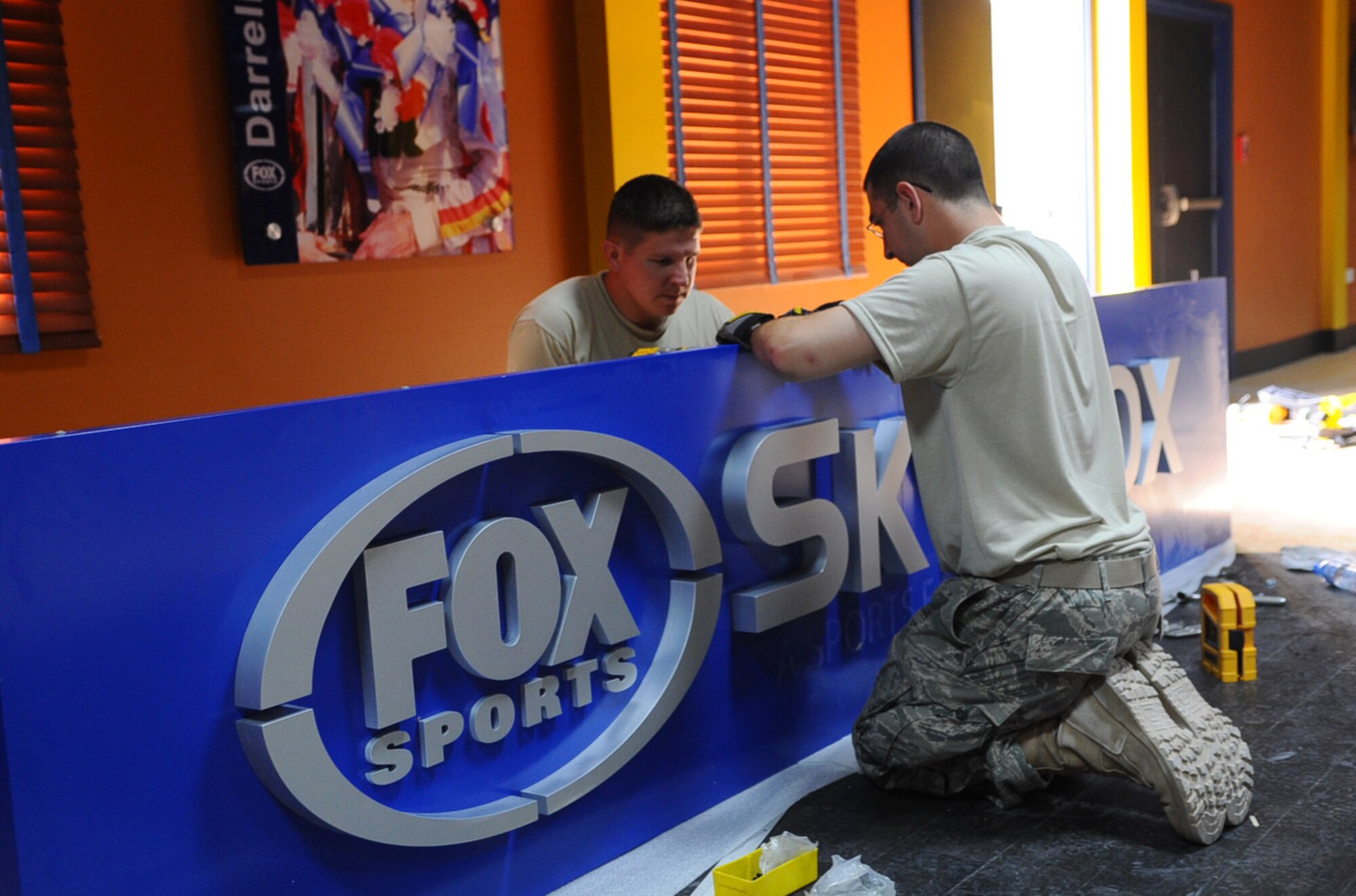 Staff Sgt. Lewis Wilder (behind the sign) and Airman 1st Class Timothy Craig, 379th Expeditionary Civil Engineer Squadron structures flight, mount brackets to the Fox Sports Sky Box?s sign before it going up at an undisclosed Southwest Asia location June 17, 2010. (U.S. Air Force photo by Senior Airman Kasey Zickmund/Released)