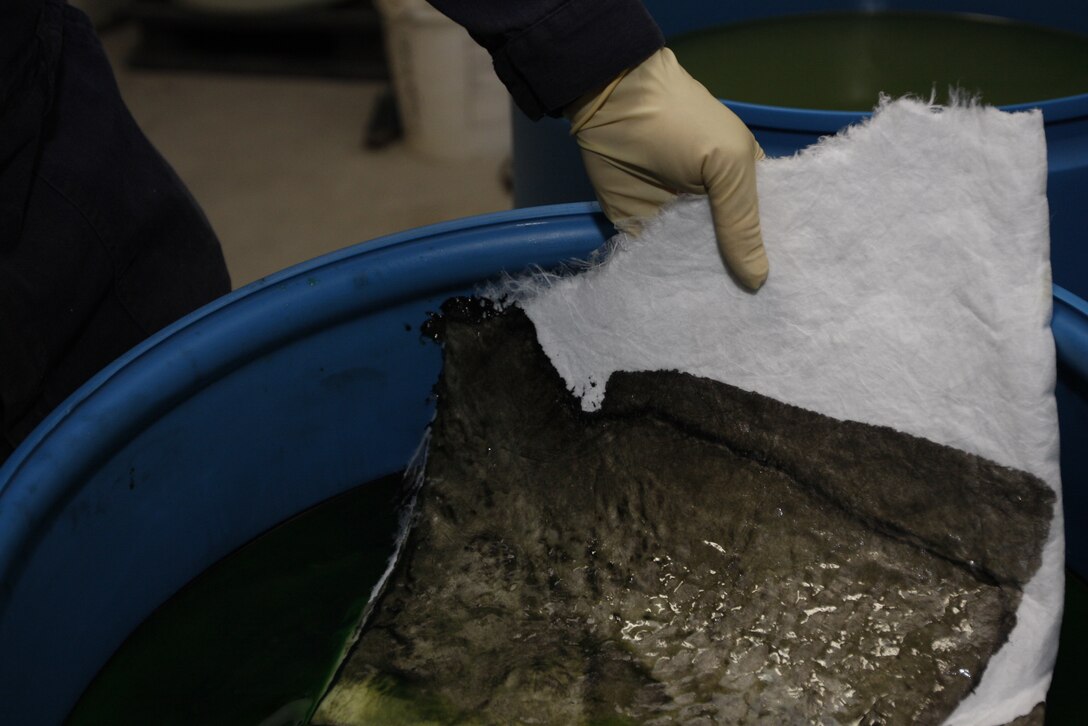 Carl Atchley, a hazardous material identifier with the Combat Center's Hazardous Material Management Branch, skims oil off the top of anti-freeze before it is re-processed Tuesday at the branch's compound. The branch recycled 12,000 gallons last year.