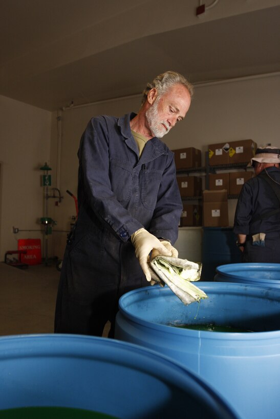 Carl Atchley, a hazardous material identifier with the Combat Center's Hazardous Material Management Branch, skims oil off the top of anti-freeze before it is re-processed Tuesday at the branch's compound. The branch saved almost $1 million in taxpayer money last year.