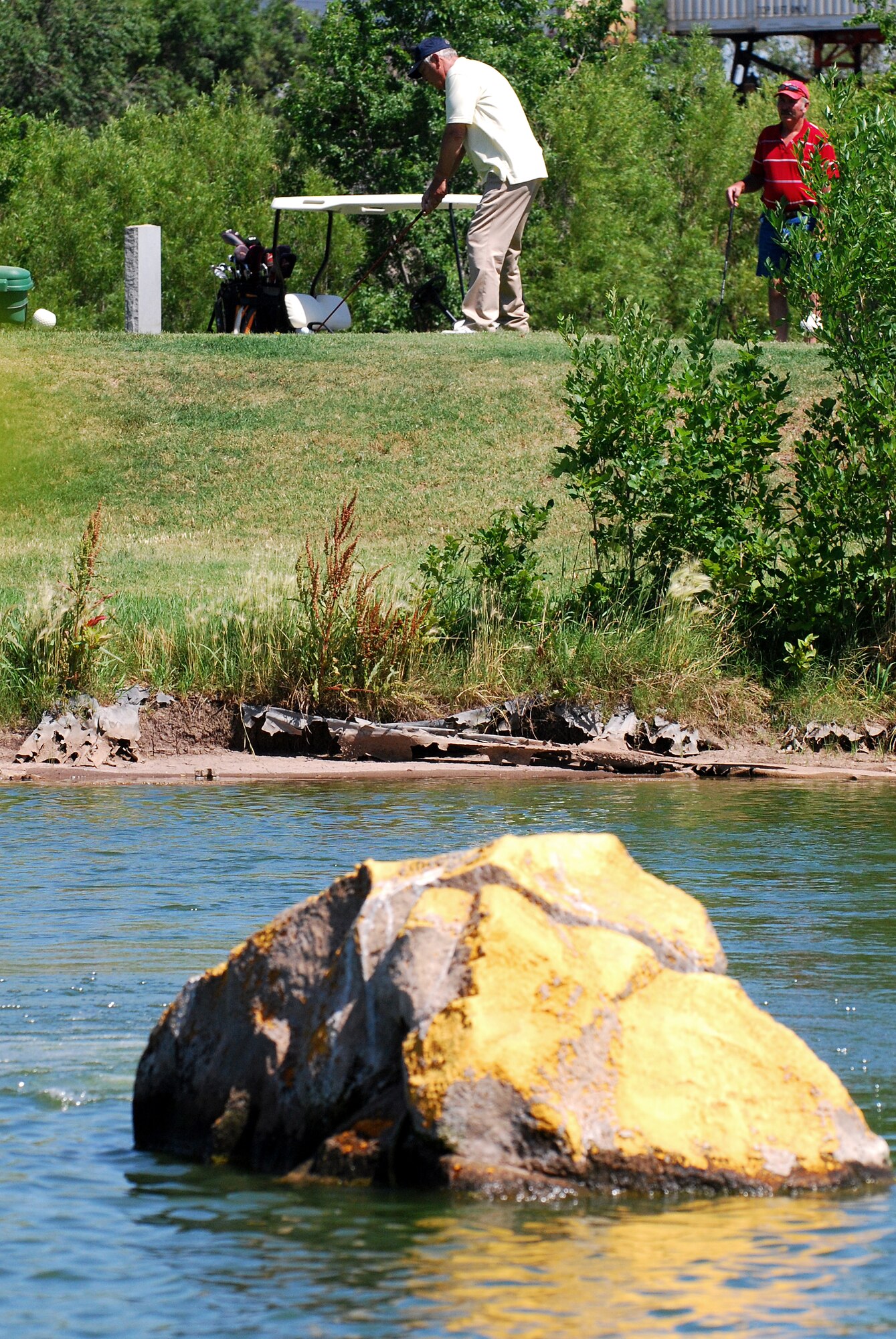 Larry Oehm watches as Mel Crossan approaches the ball in the Father's Day golf event at Cannon Air Force Base's Whispering Winds Golf Course on June 20. Both are retired Airmen who took advantage of one of their benefits.  (U. S. Air Force Photo by Master Sgt. Carlotta Holley)