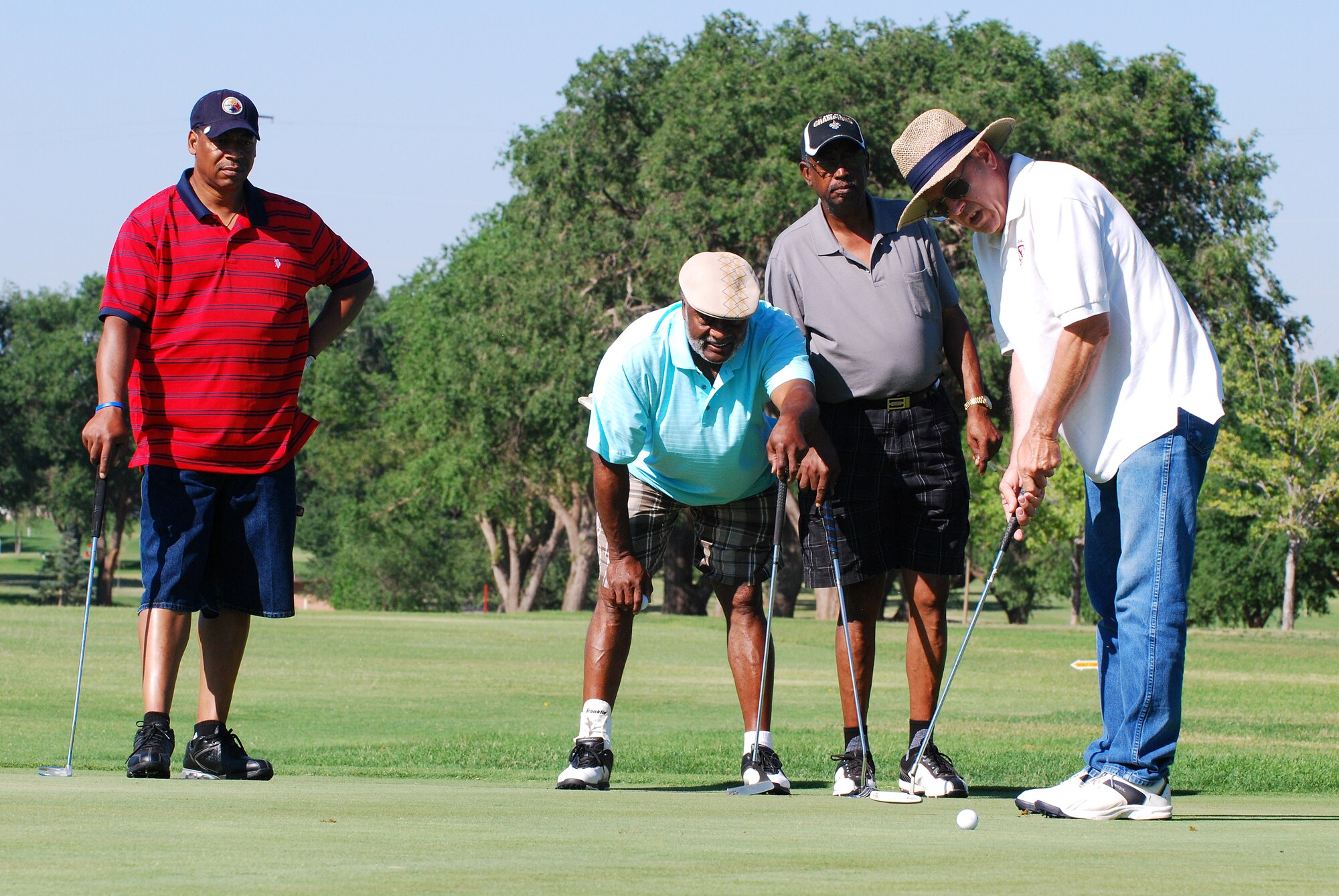 Retirees Master Sgt. Ralph Bell, Chief Master Sgt. Hank Baskett and Tech. Sgt.   Archie Broussard watch as Dan Williams lines up a shot in the Father's Day golf event at Cannon Air Force Base's Whispering Winds Golf Course on June 20. (U. S. Air Force Photo by Master Sgt. Carlotta Holley)