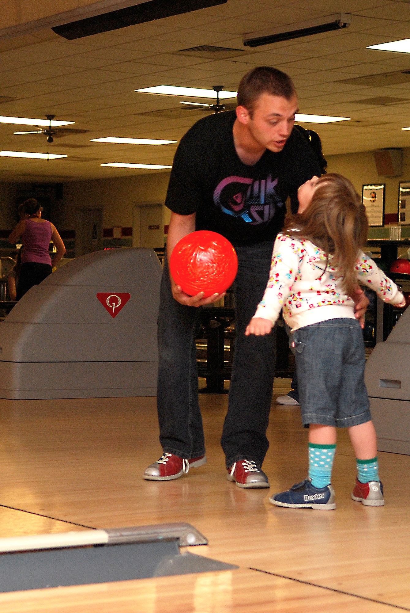 Staff Sgt. Phillip Winter, 27th Special Operations Squadron, gives his daughter, Addison, some during a Father's Day bowling event at Cannon Air Force Base's Bowling Center on June 20. (U. S. Air Force Photo by Master Sgt. Carlotta Holley)