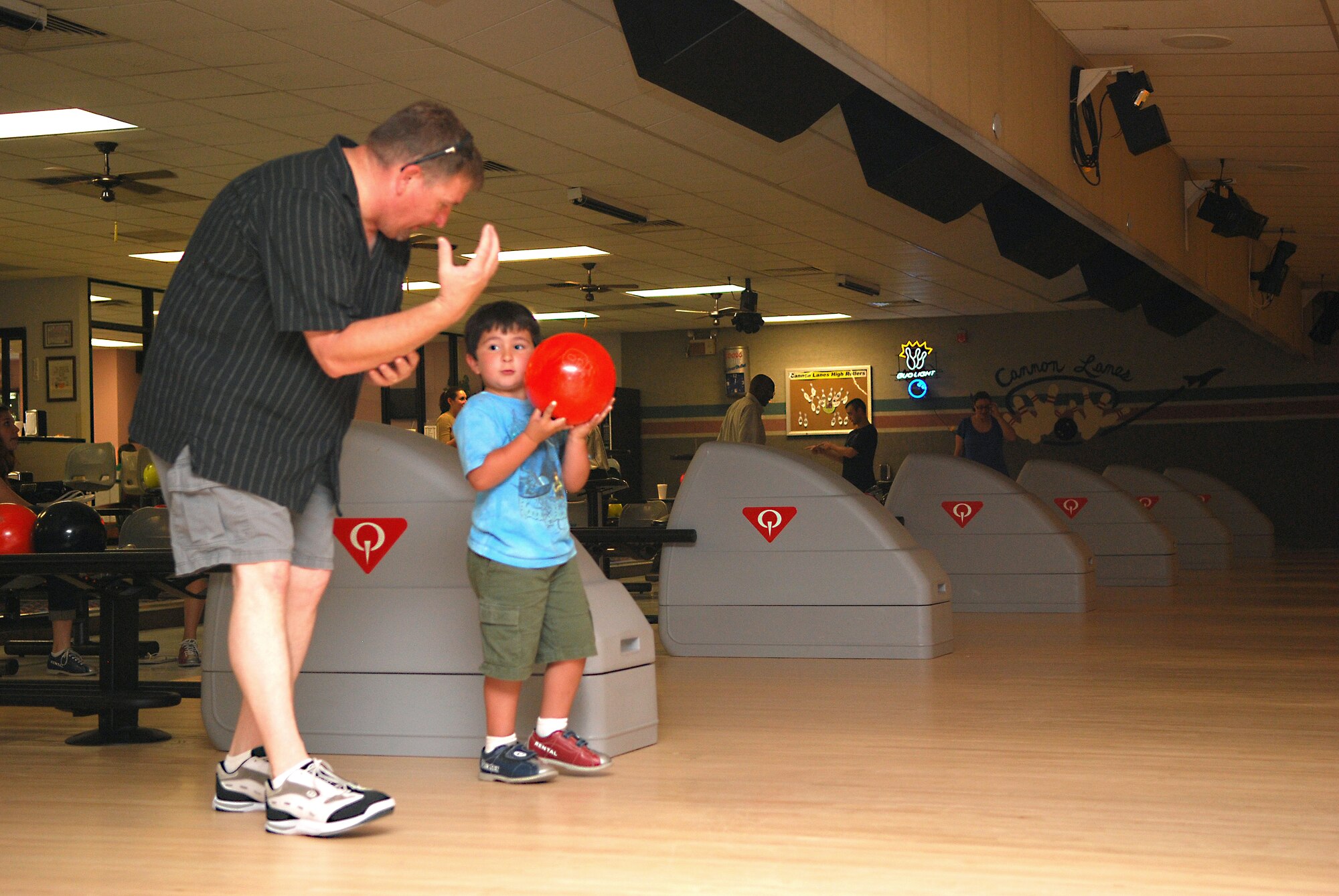 Retired Master Sgt.  Paul Walton, a contractor with the 3rd Special Operations Squadron, assists his son, Chase, on Father's Day bowling event at Cannon Air Force Base's bowling center on June 20. (U. S. Air Force Photo by Master Sgt. Carlotta Holley)