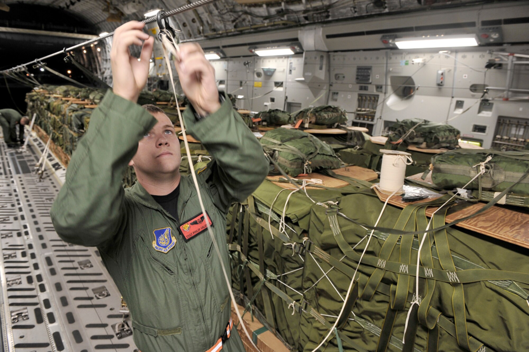 Staff Sgt. Philip Vallenta reinforces a container delivery system bundle in preparation for a 25-bundle airdrop totaling more than 90,000 pounds June 24, 2010, while at Joint Base Pearl Harbor- Hickam, Hawaii, in support of the Rim of the Pacific exercise. This is the 22nd year of RIMPAC, a biennial exercise that promotes the interoperability of more than 14 partner nations as a key element of regional stability. Sergeant Vallenta is a 535th Airlift Squadron loadmaster. (U.S. Air Force photo/Tech. Sgt. Cohen A. Young) 