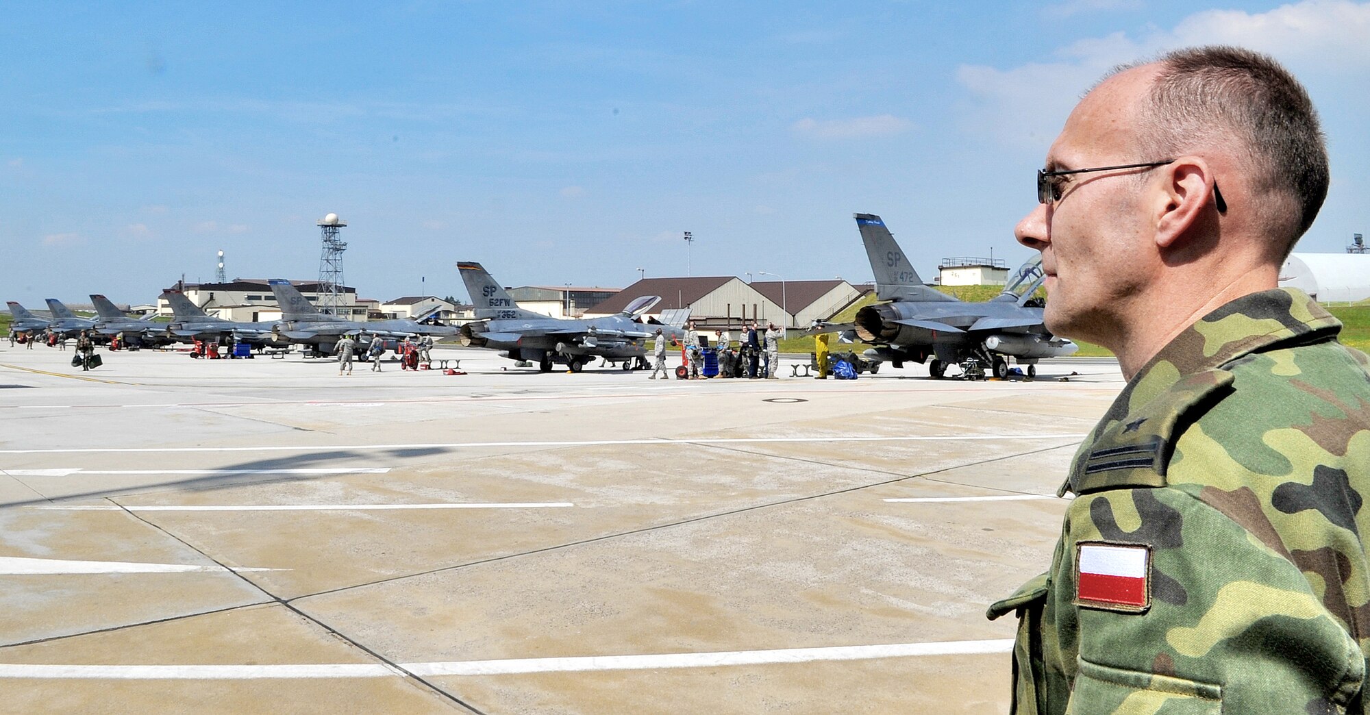 Polish air force Maj. Andriej Pokladek observes Airmen from the 52nd Aircraft Maintenance Squadron perform maintenance on F-16 Fighting Falcons during a U.S. Air Forces in Europe Operational Readiness Inspection June 23, 2010 at Spangdahlem Air Base, Germany. Members from headquarters USAFE and Aviano Air Base, Italy, 31st Fighter Wing escorted their Polish counterparts during the USAFE ORI. The Polish air force's 32nd Tactical Air Base, Poland, will have its first practice NATO tactical evaluation in August. Major Pokladek is assigned to the Polish Air Force's 32nd ATB. (U.S. Air Force photo/Airman 1st Class Nick Wilson)