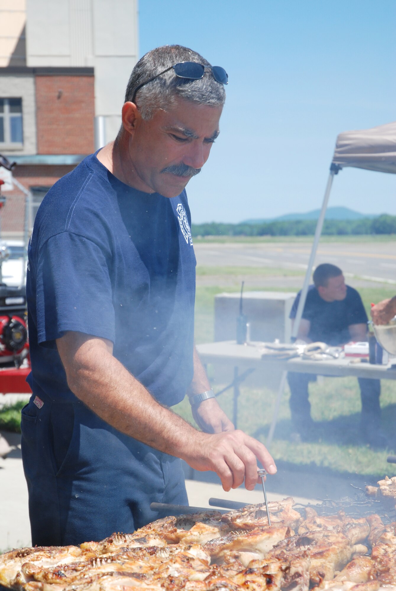 Westover firefighter Luis Carvalho checks the temperature of chicken being prepared for the June 25 cookout fundraiser at the base fire department.  The firefighters, who are members of the Federal Firefighters Benevolent Association, raise money year-round for Westover members in need and for the burn unit at the Shriner's Hospital for Children in Boston.  The cookout raised about $1000.