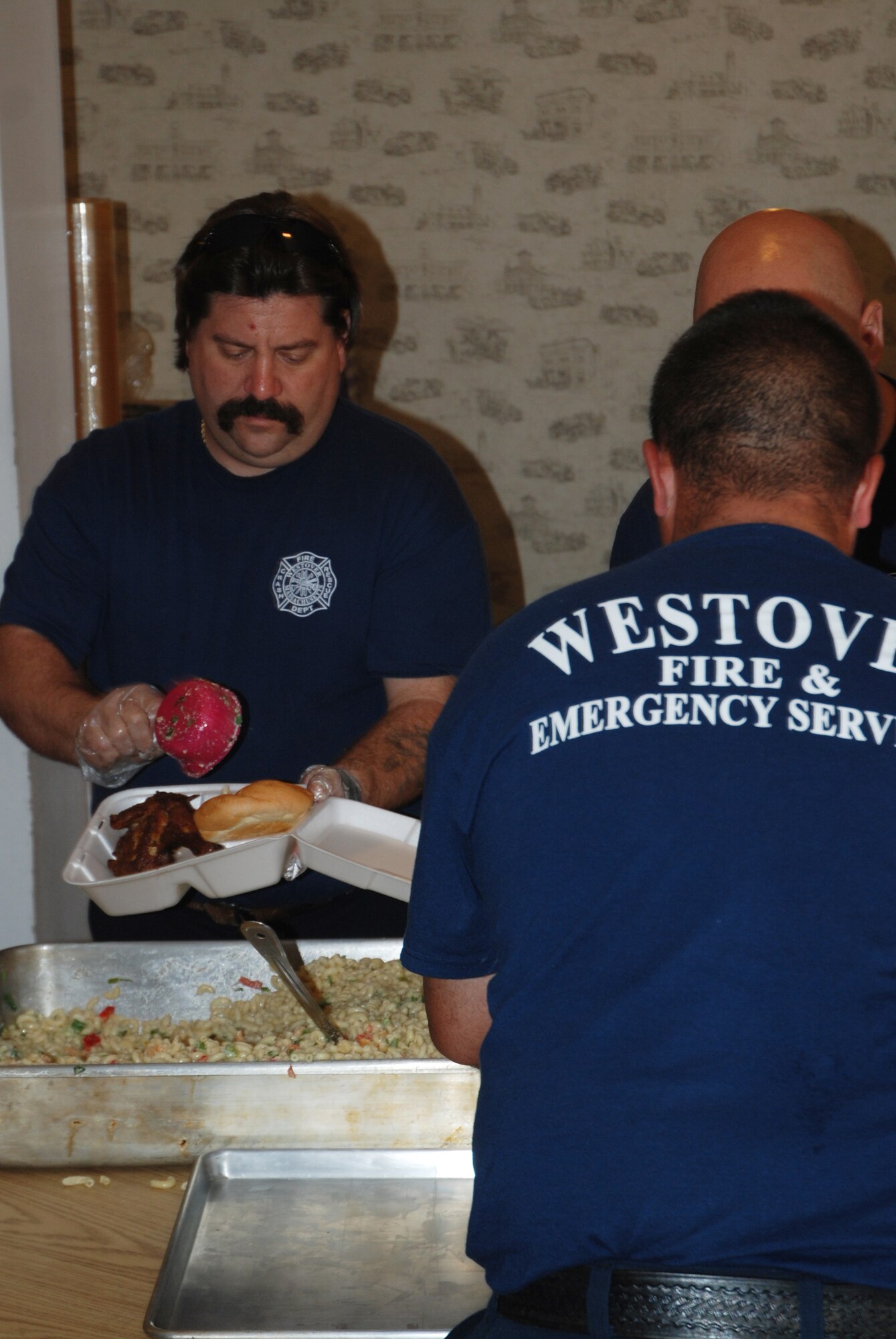 Westover firefighter Robert Mancini fills to-go trays with macaroni salad during the fire department's barbecue fundraiser June 25.  The firefighters, who are members of the Federal Firefighters Benevolent Association, raise money year-round for Westover members in need and for the burn unit at the Shriner's Hospital for Children in Boston.  The cookout raised about $1000.
