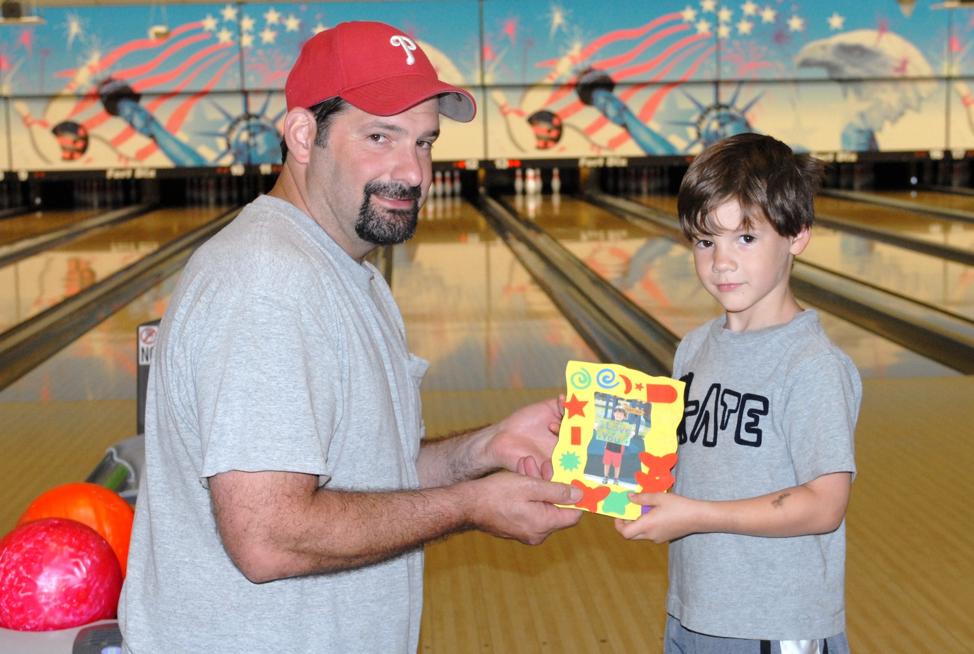 Brian Falkenstein, husband of Sgt. 1st Class Lynette Falkenstein, and their son, Andrew, 5, display the Father's Day gift Andrew made at the Child Development Center. The Falkenstein family participated in the Father's Day bowling event, sponsored by the 1st Battalion, 309th Regiment's Family Readiness Group Monday.