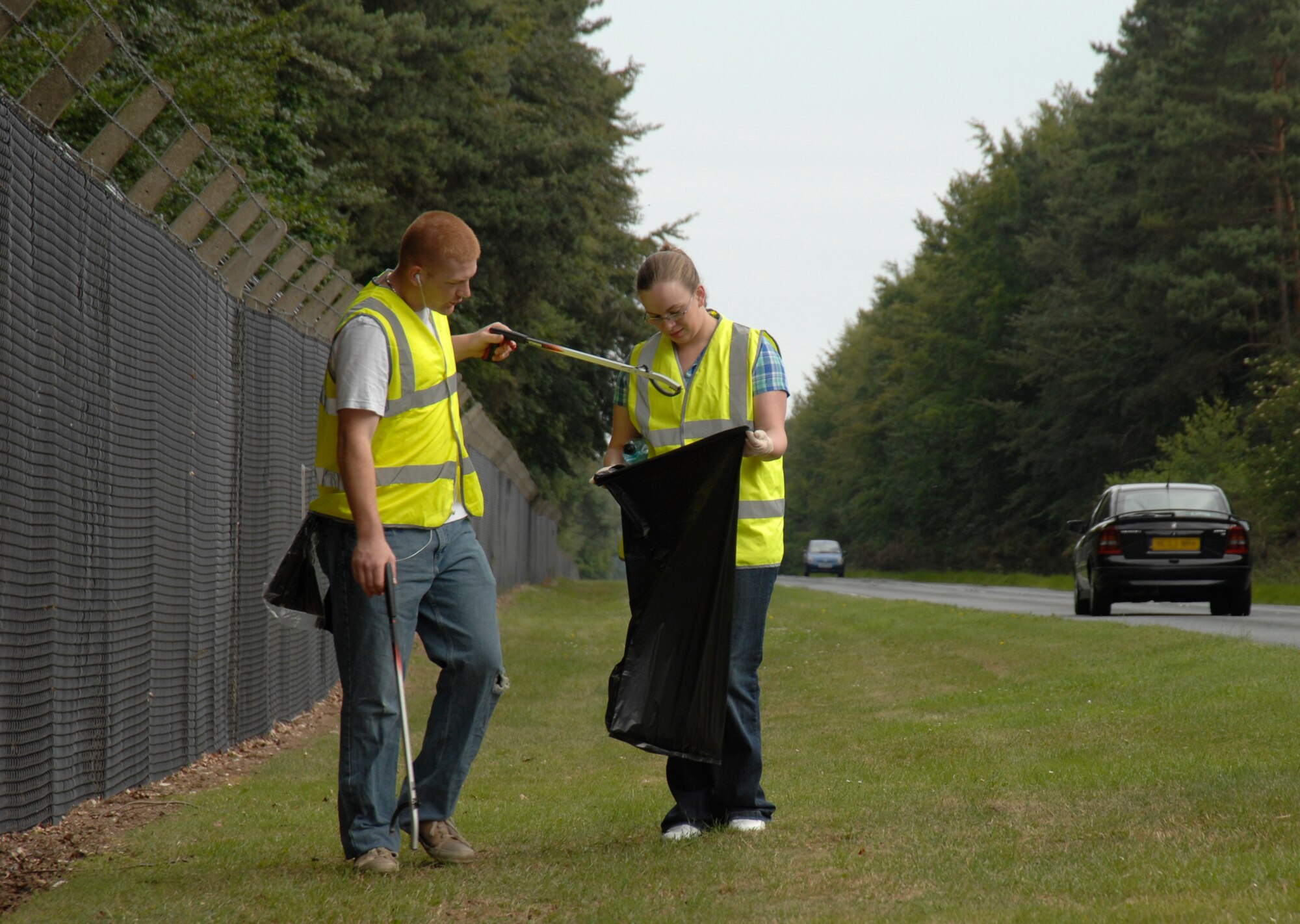 Airmen 1st Class Kipp Baldwin and Amanda White of the 48th Civil Engineer Squadron collect refuse along the road outside RAF Lakenheath, England, during a Litter Pick June 26. Volunteers removed 30 bags of trash from the two-mile stretch of road. (U.S. Air Force photo/Senior Airman David Dobrydney)