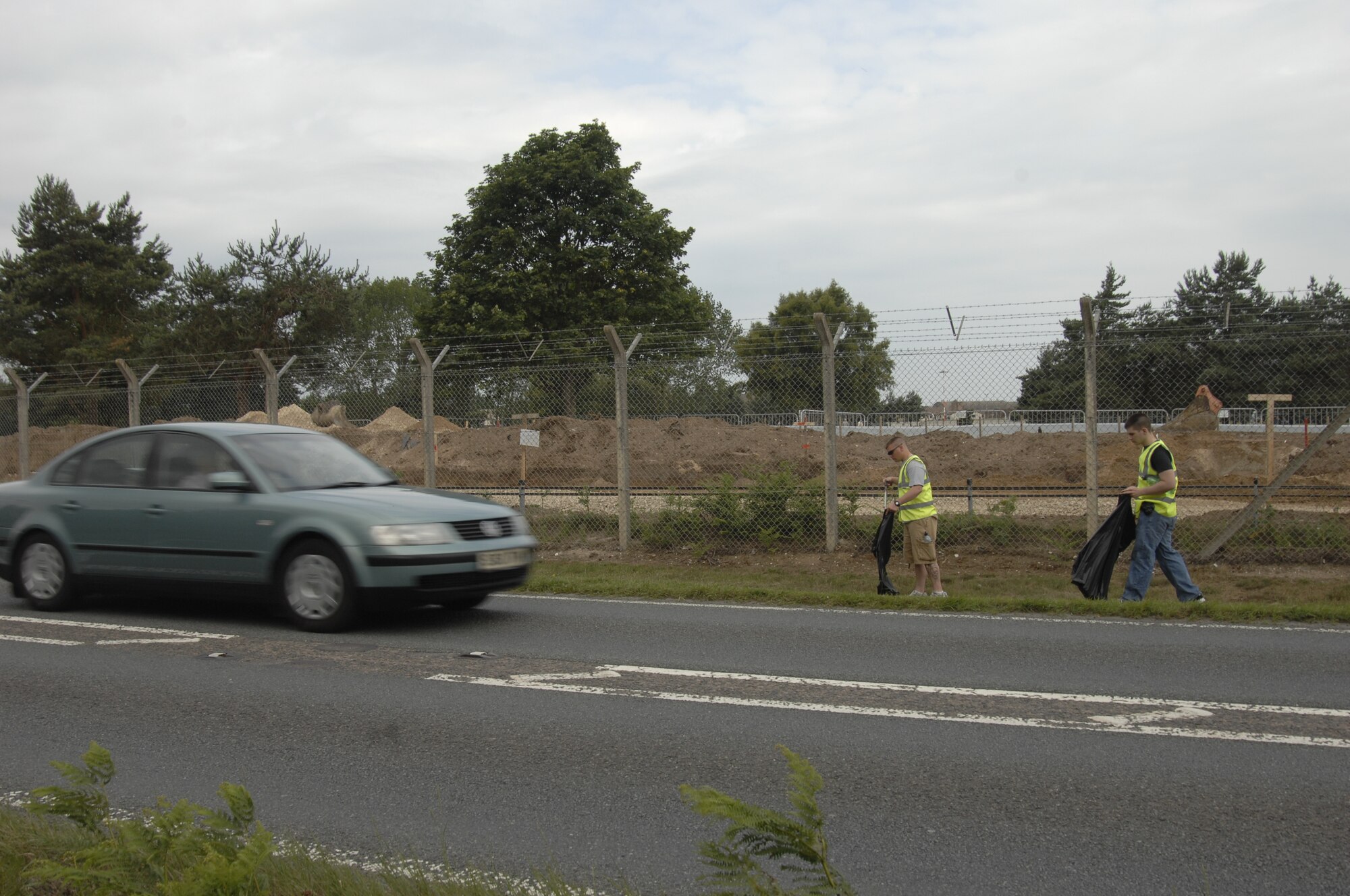 Staff Sgt. Chad Baker and Senior Airman Jason Wright of the 48th Security Forces Squadron make their way along the fence outside RAF Lakenheath, England during a Litter Pick June 26. Twenty-five volunteers turned out to clean a two-mile stretch of road. (U.S. Air Force photo/Senior Airman David Dobrydney)